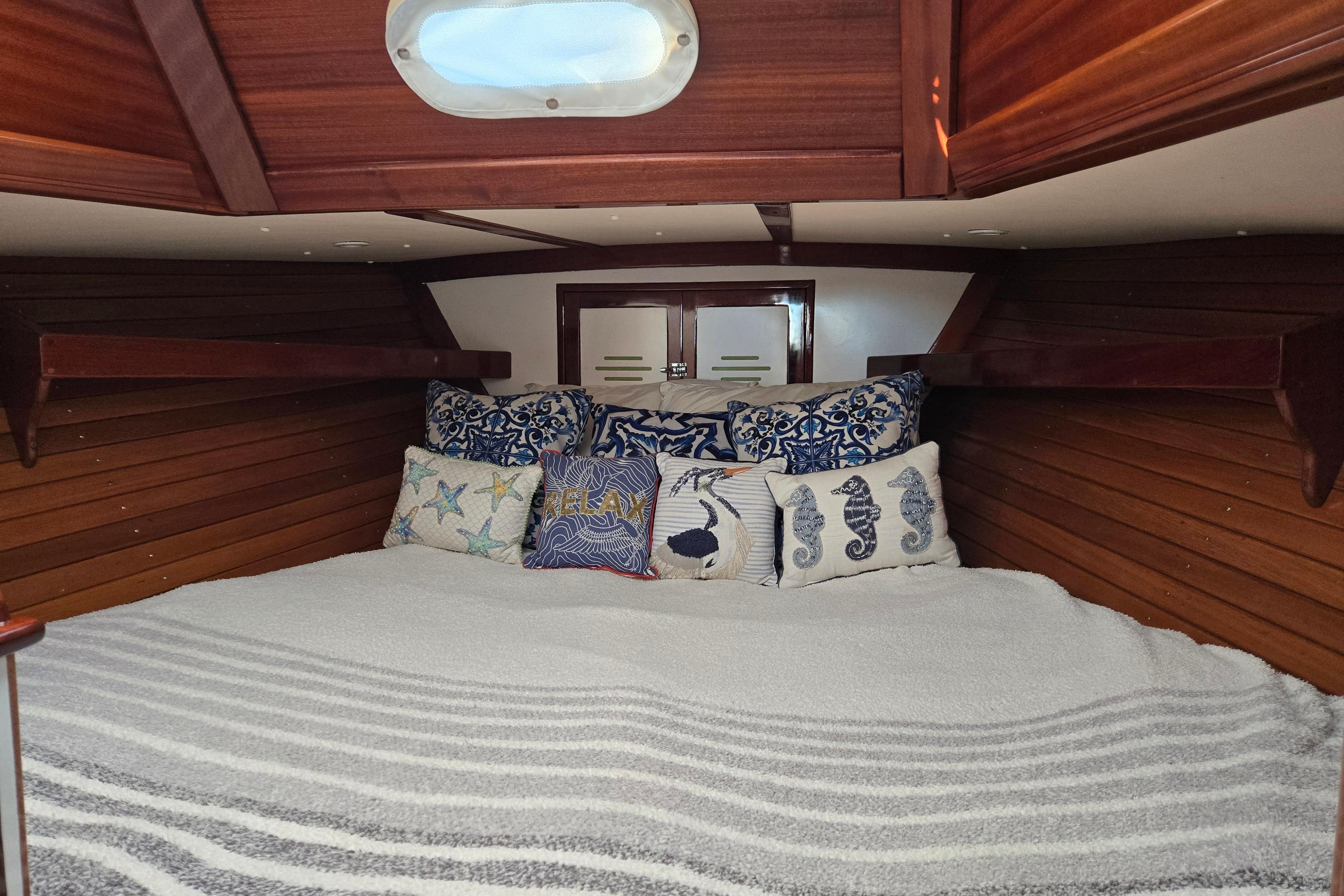 Cozy cabin interior of a 1970 Hinckley Bermuda 40 sailboat with nautical-themed pillows.