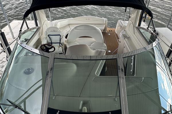 2004 Sea Ray 380 Sundancer cockpit with white seating and steering wheel, docked by the water.
