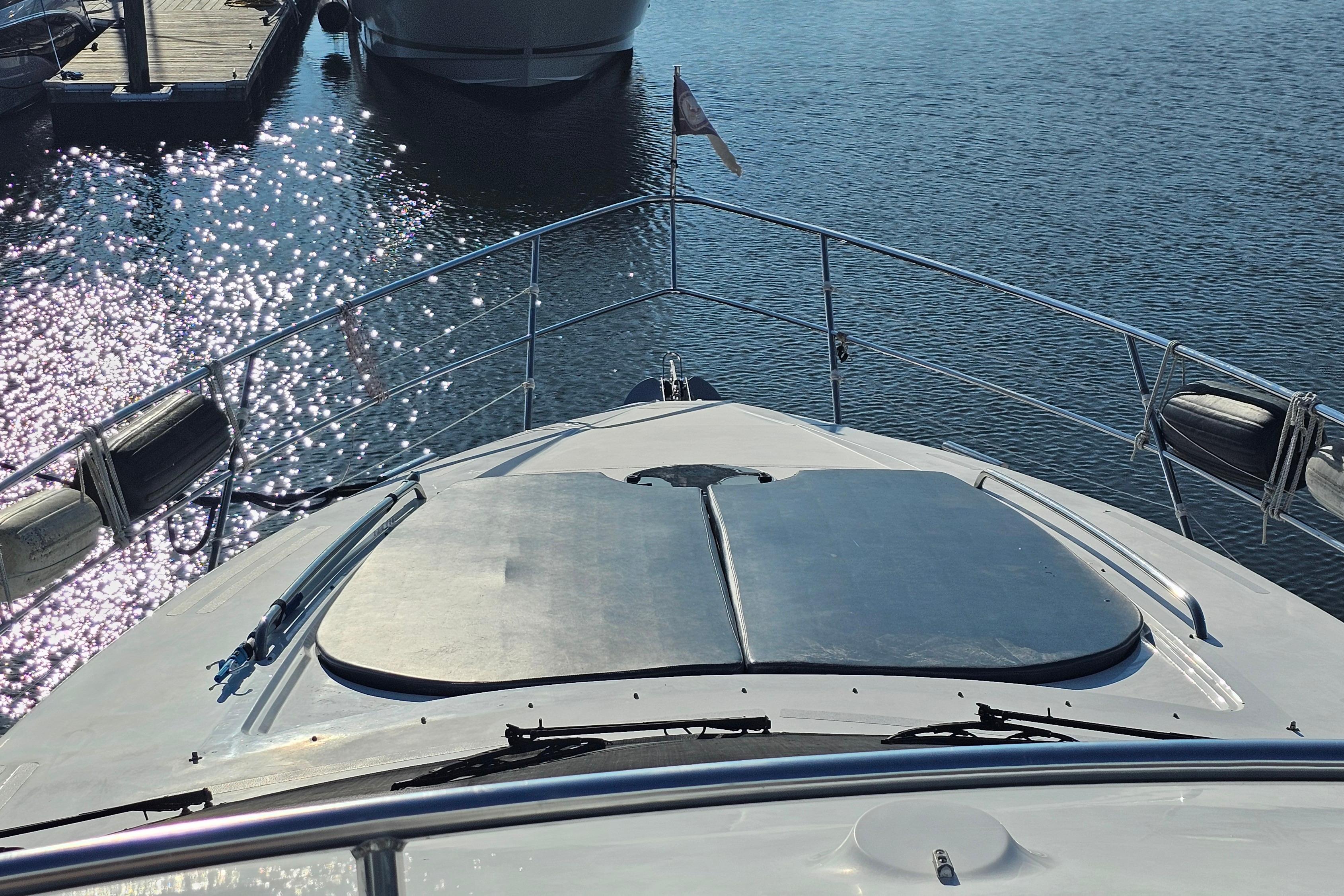 Bow view of 2005 Neptunus 56 Flybridge yacht docked on sparkling water.
