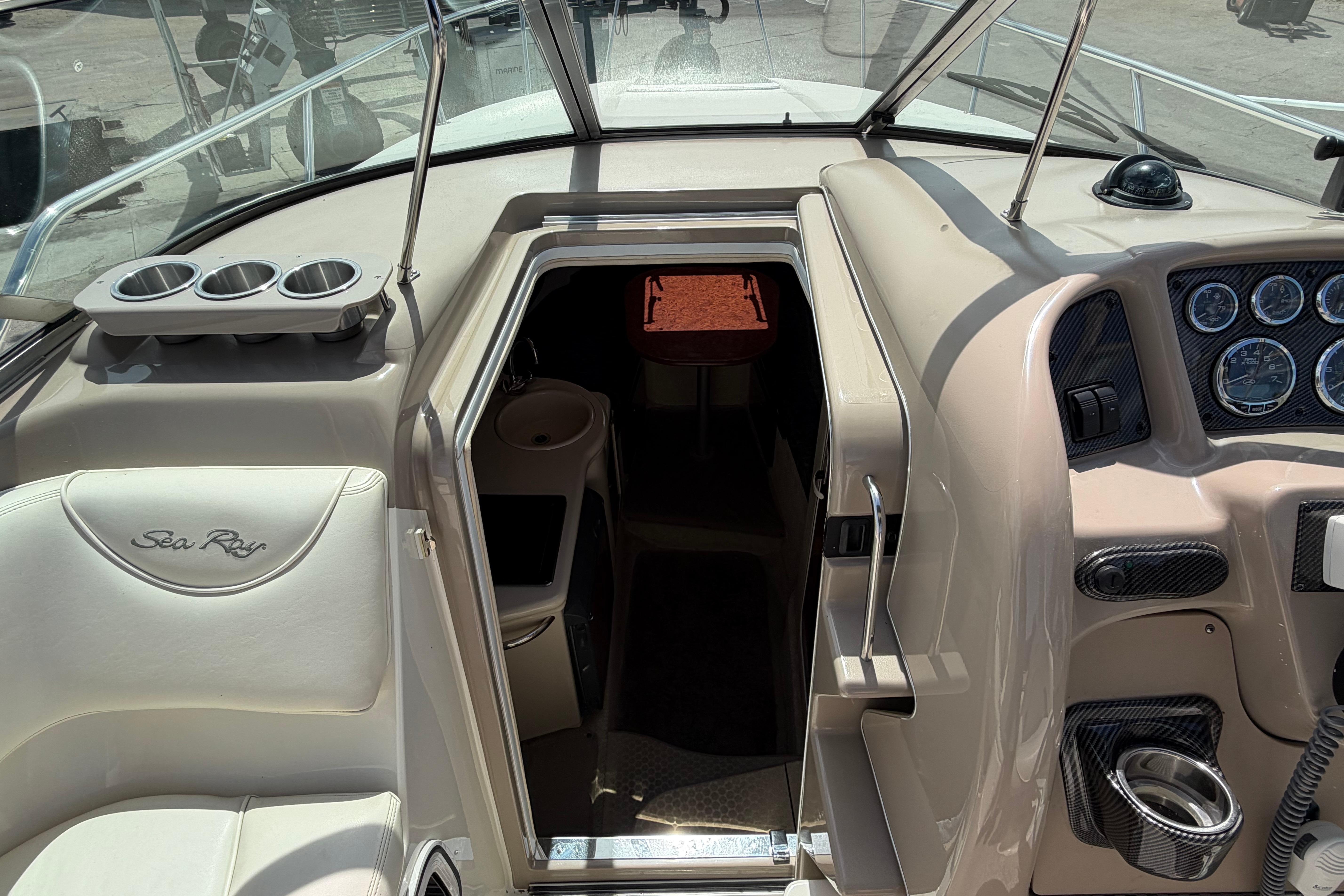 2004 Sea Ray Sundancer 260 cockpit with helm, gauges, and cabin entrance.