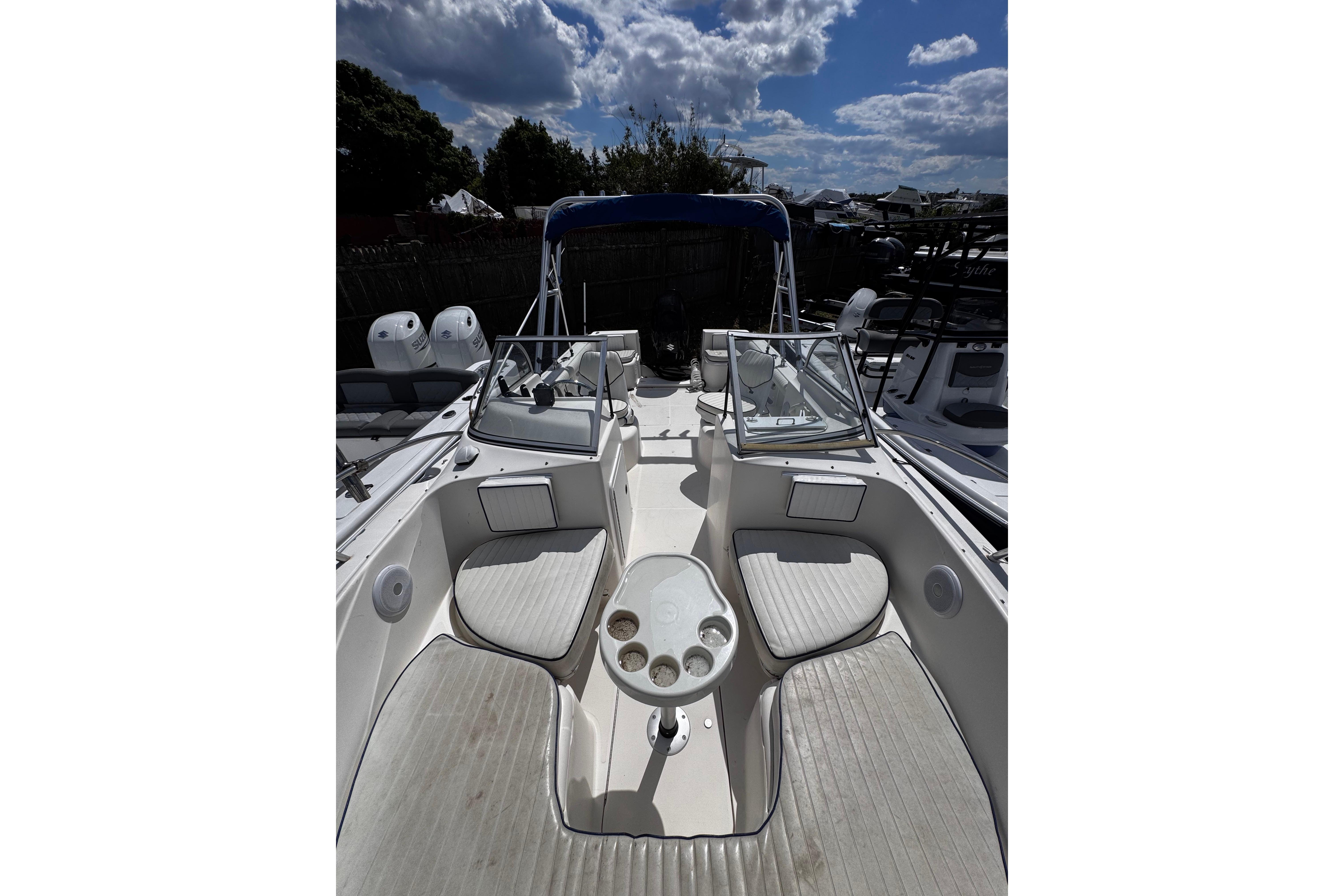 2003 Palm Beach 2200 Dual Console boat with seating and cup holders under a cloudy sky.