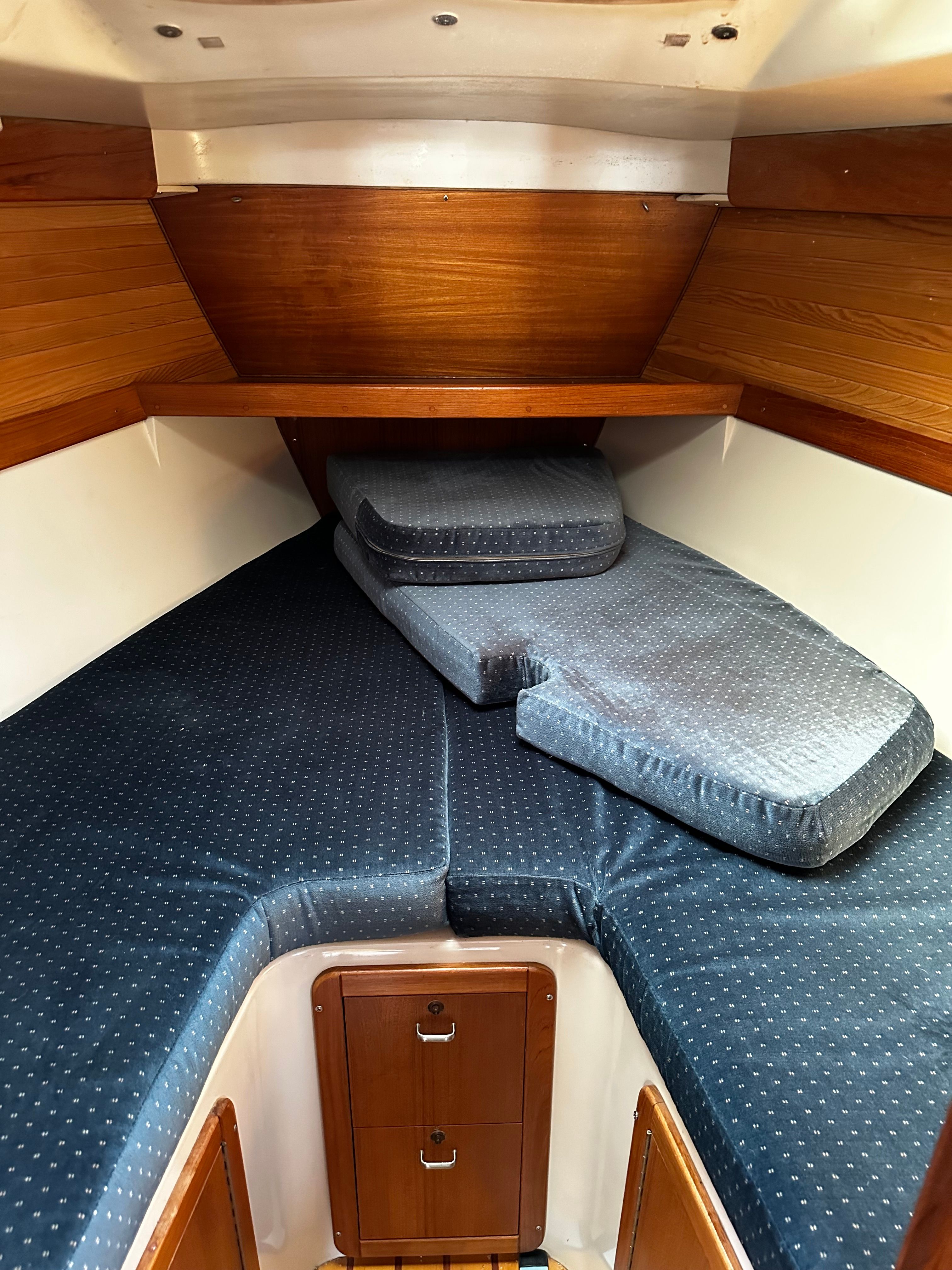 Interior of a sailboat with blue cushions and wooden walls.