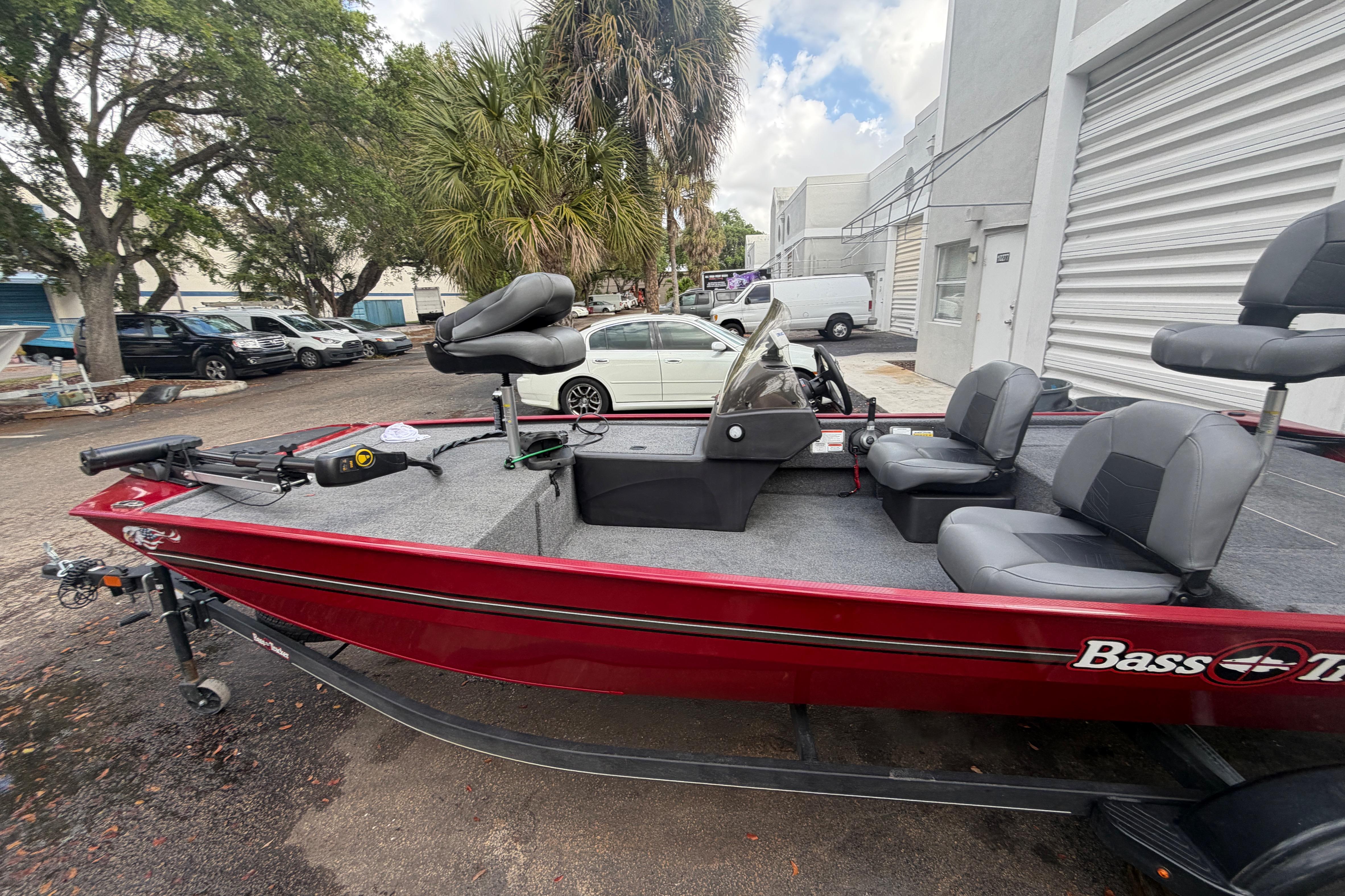 2023 Bass Tracker III Classic boat, red exterior, parked outdoors near trees and buildings.