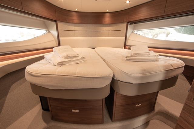 Luxurious 2024 Princess V55 yacht cabin with twin beds and elegant wood finish.