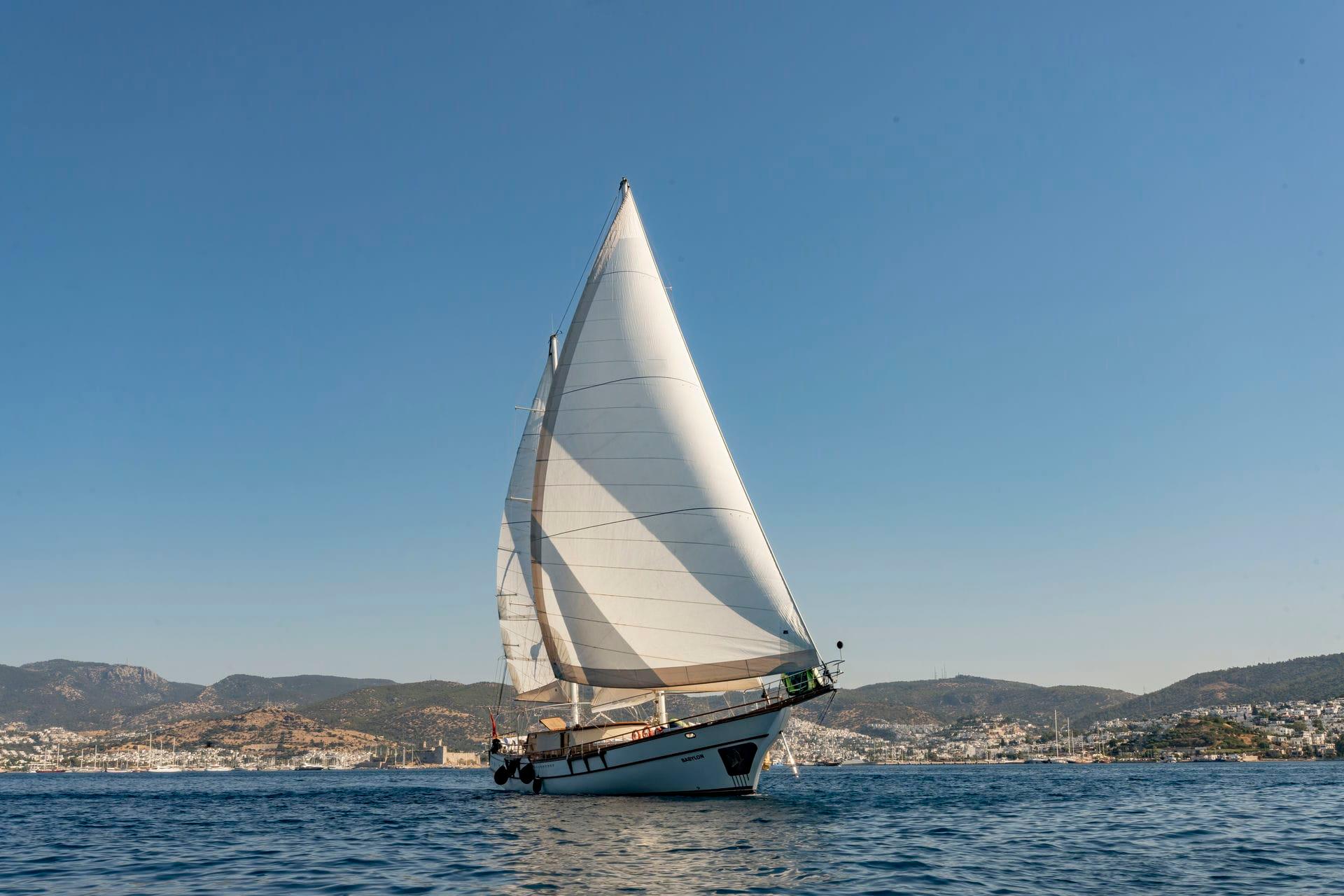 Sailboat on calm sea with distant hills under clear blue sky, Custom model 134, 2015.