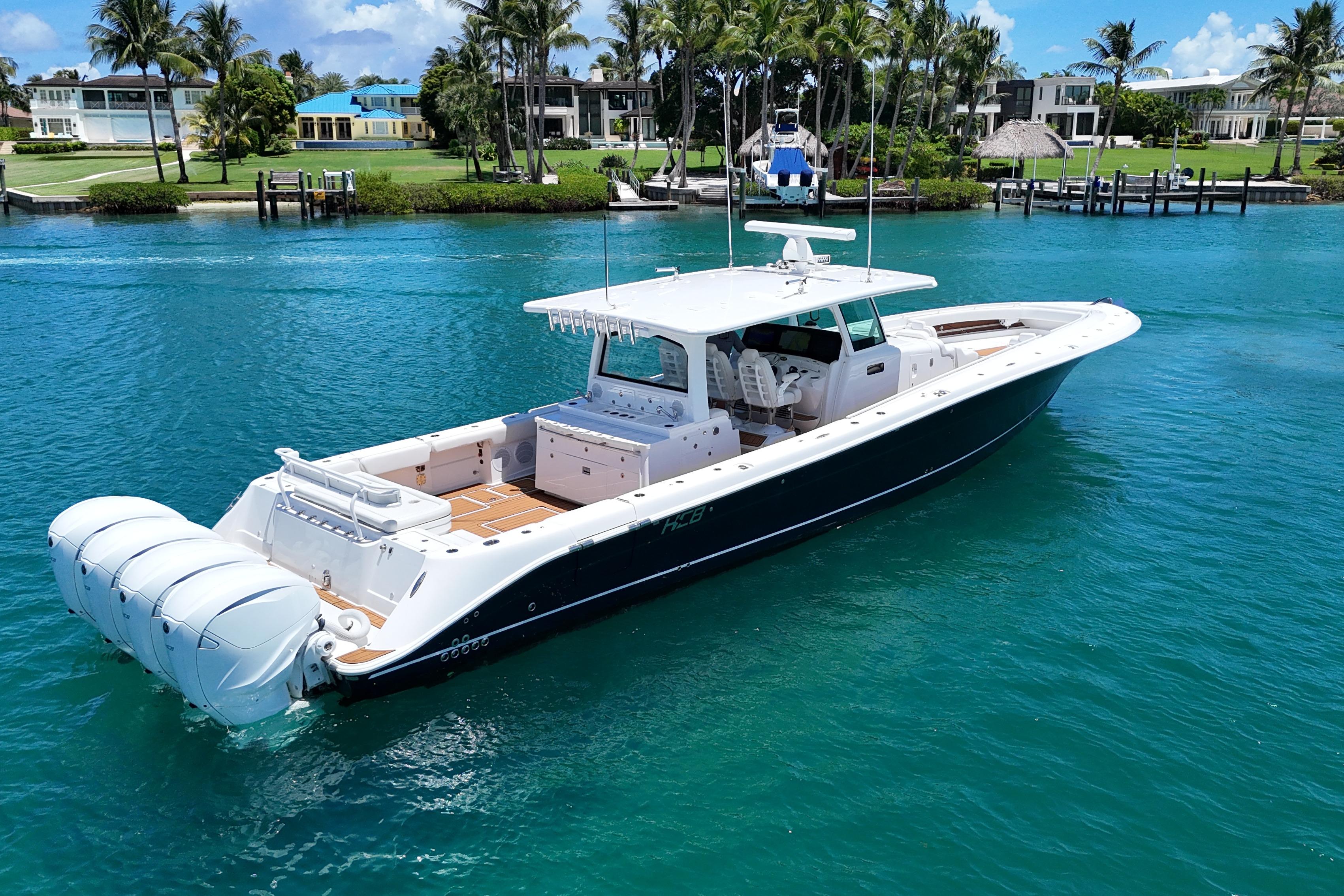 2020 HCB 53 Sueños luxury boat on clear blue water, surrounded by palm trees.