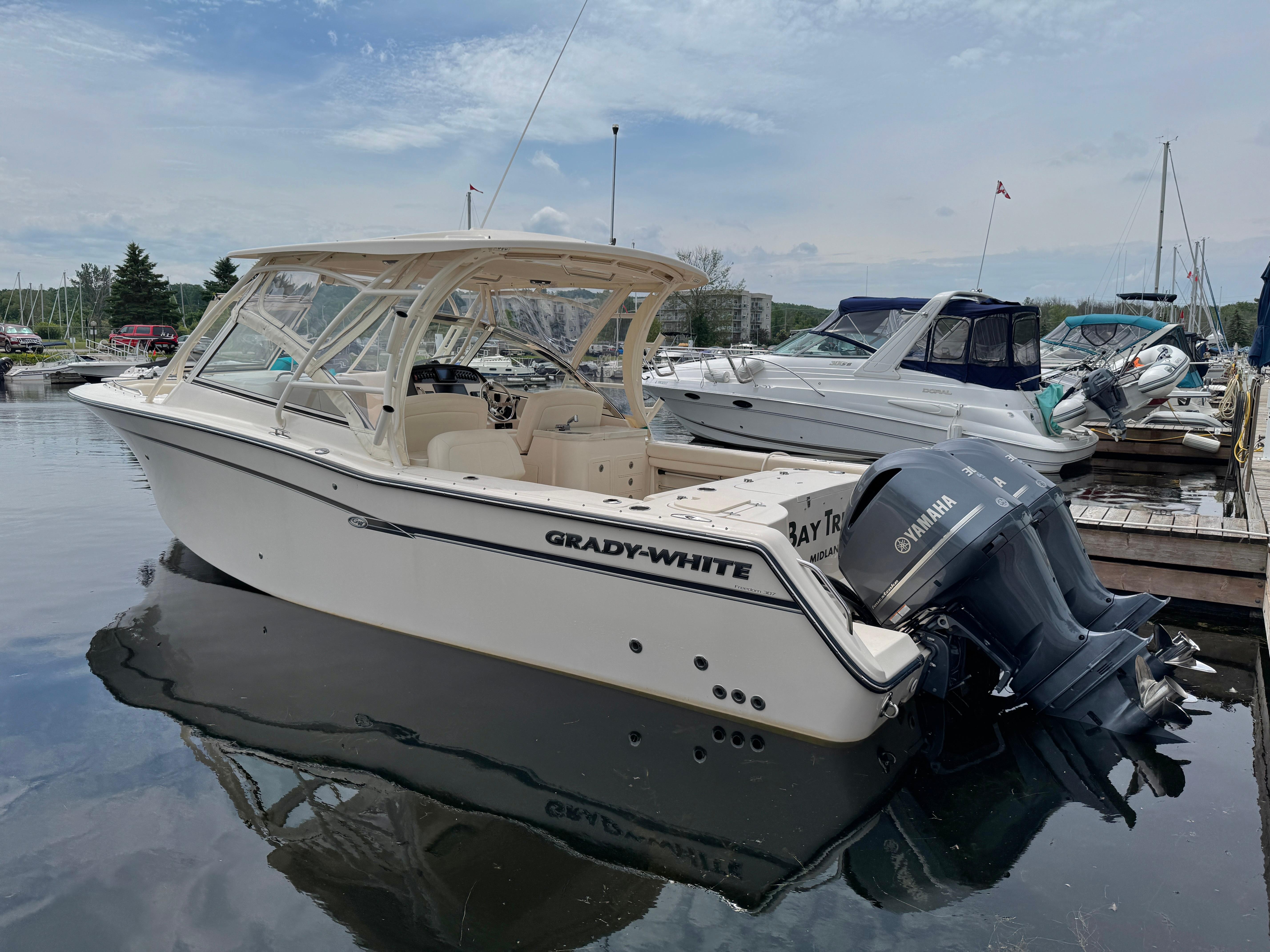 2019 Grady-White Freedom 307 boat docked with Yamaha engines, under a cloudy sky.
