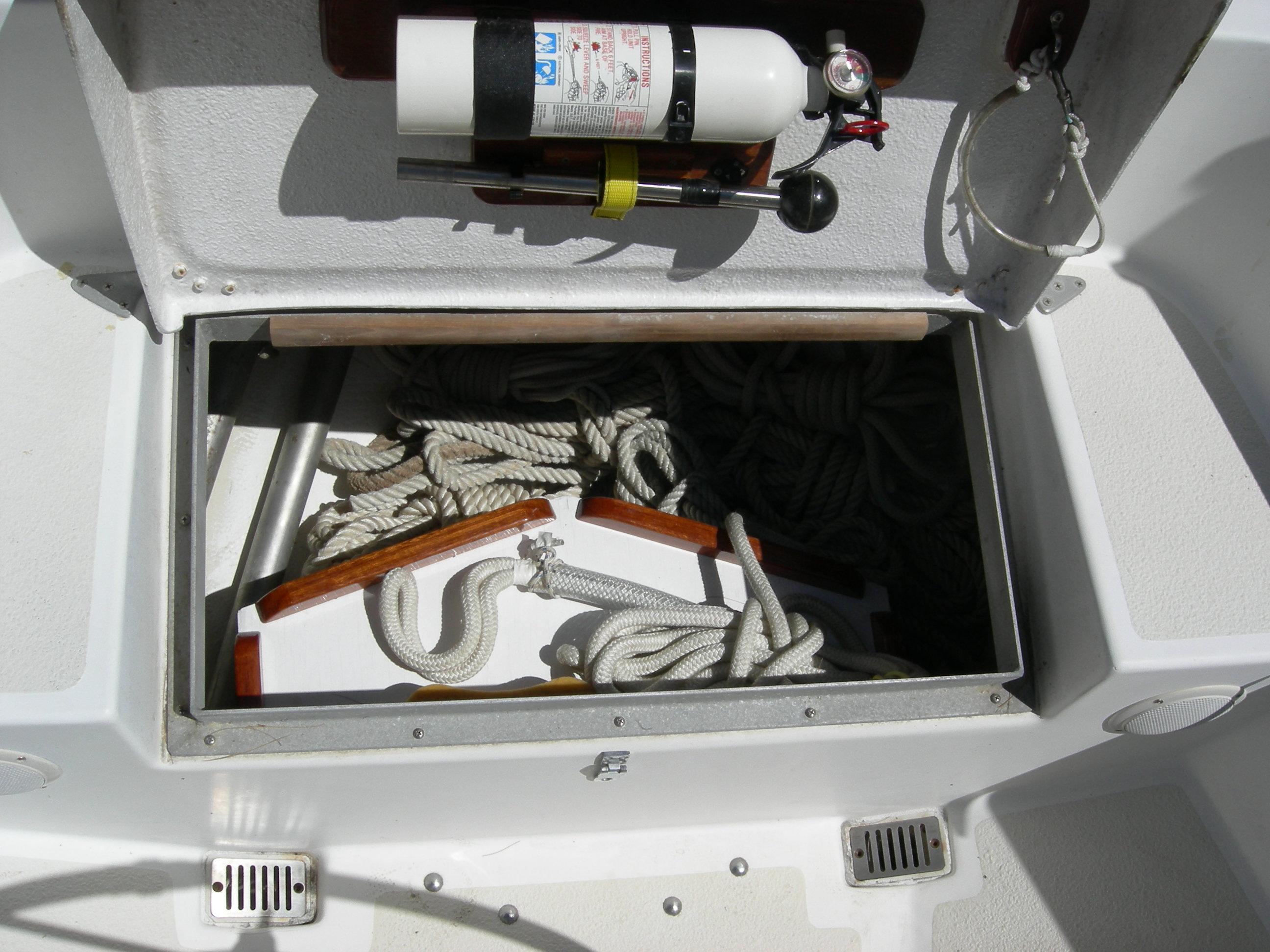 Open storage compartment on 1982 Morgan 32 boat with ropes and fire extinguisher.