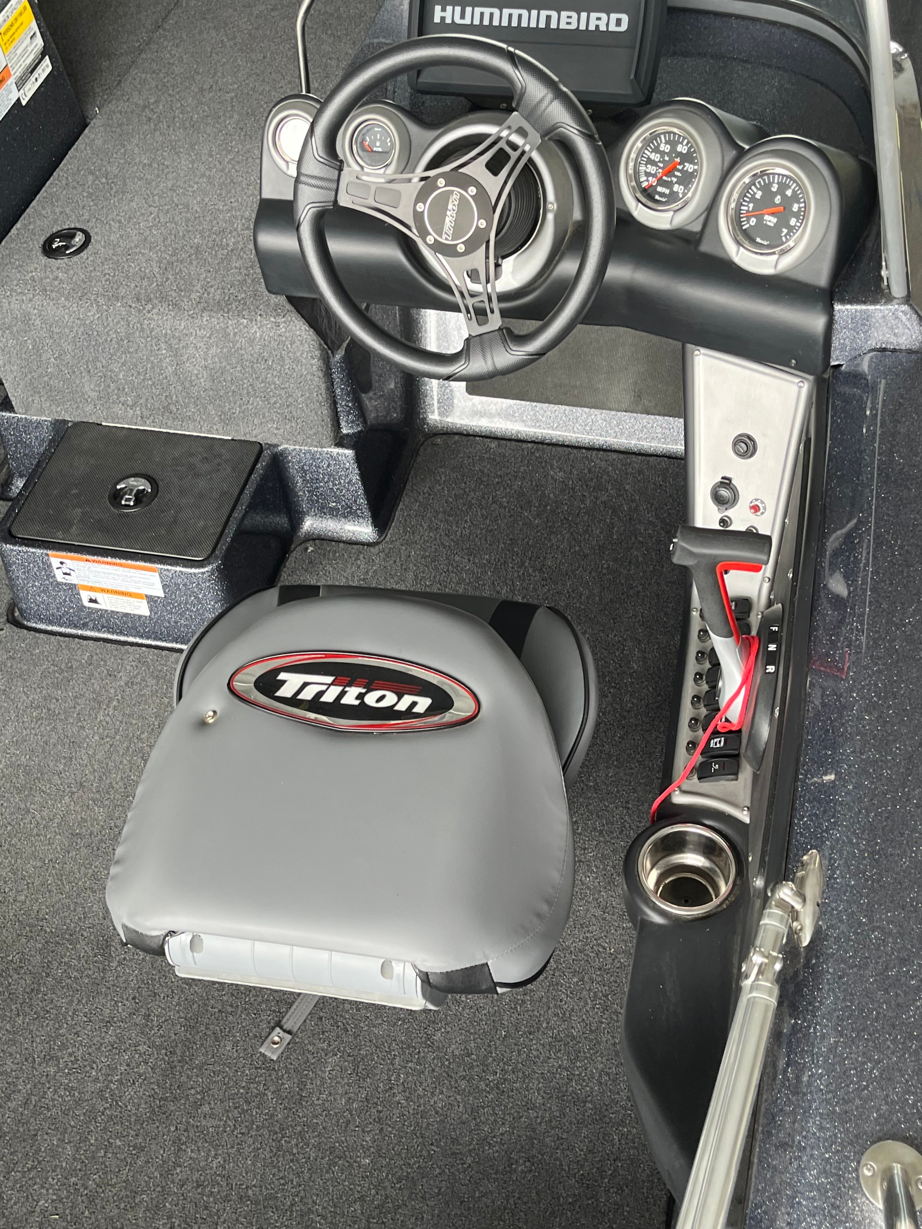 The image shows the cockpit of a Triton 186 Fishunter boat with a steering wheel and instruments.