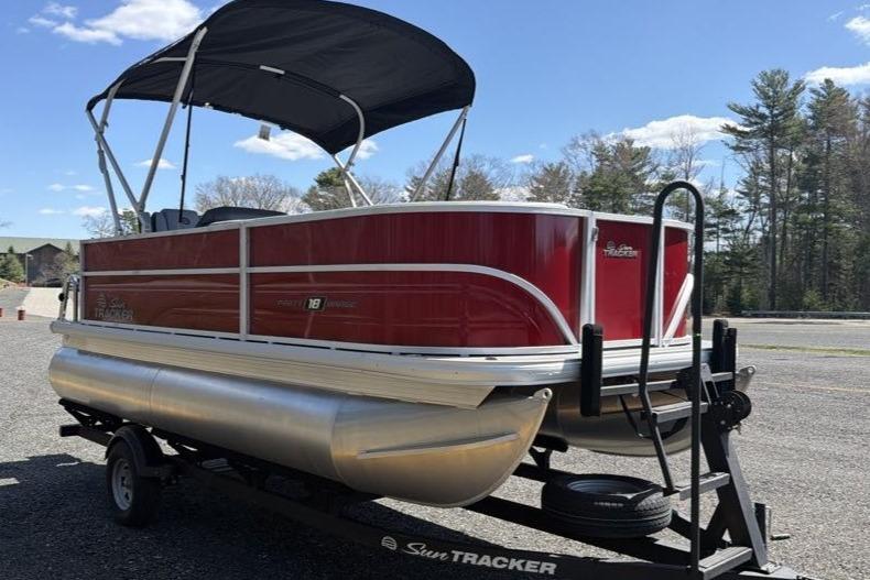 2026 Sun Tracker Party Barge 18 DLX pontoon boat on trailer, red exterior, sunny day.