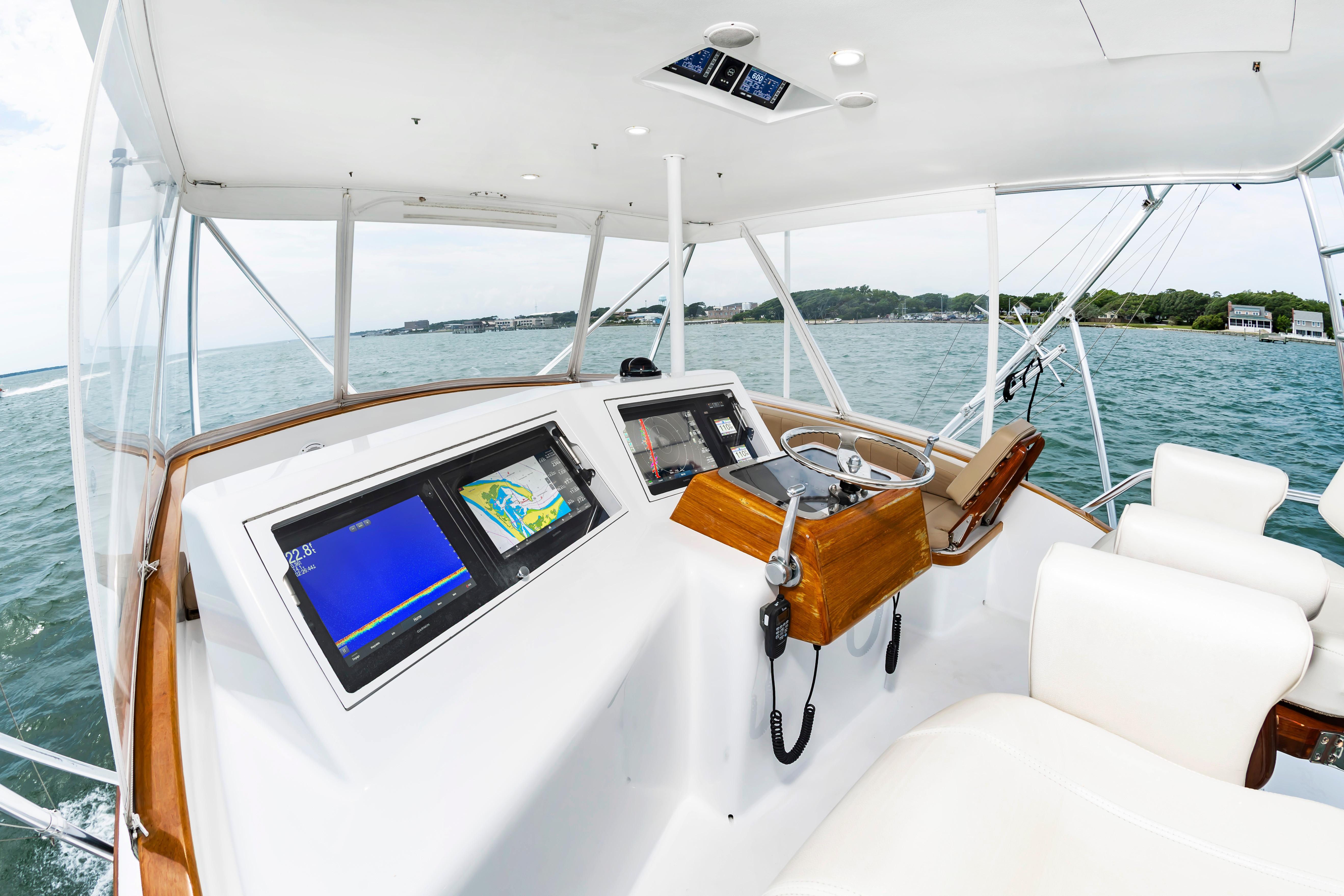 Helm of 1993 Custom Carolina Scarborough 56 Convertible yacht with navigation screens and steering wheel.