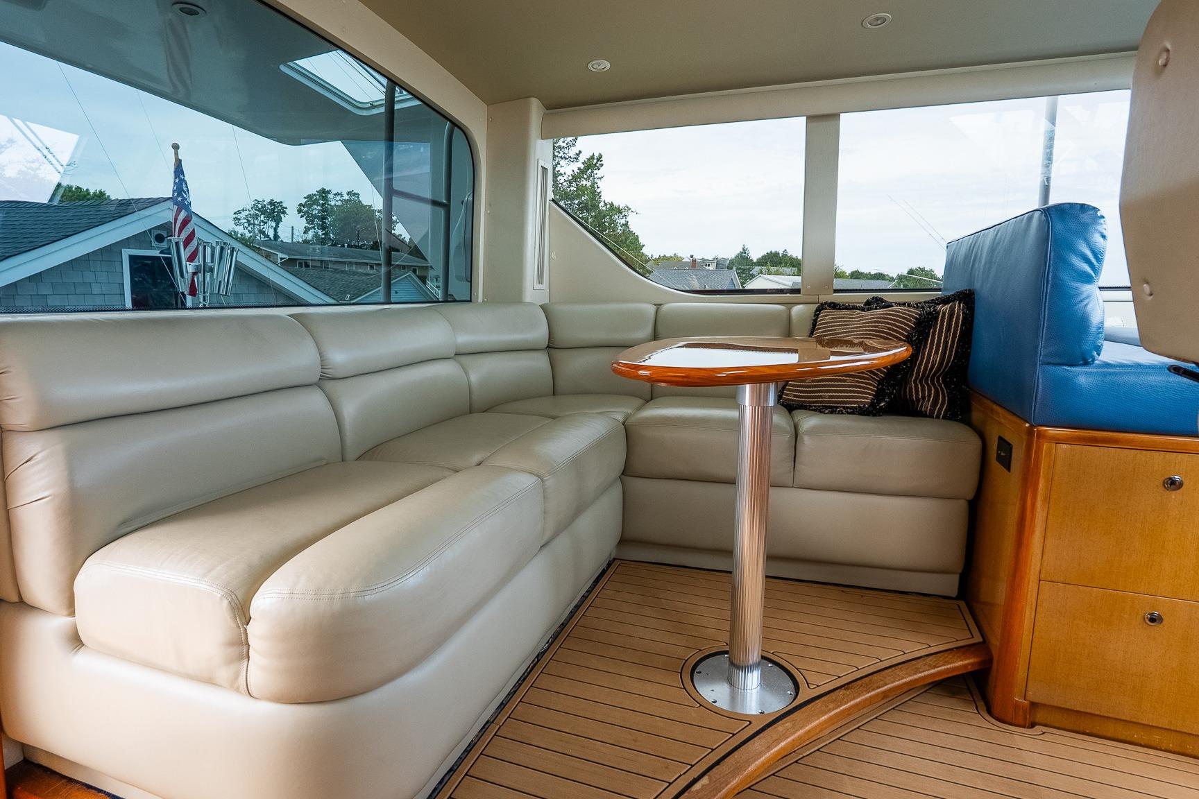Luxurious interior of 2002 Viking 61 Enclosed Bridge yacht with leather seating and wooden table.