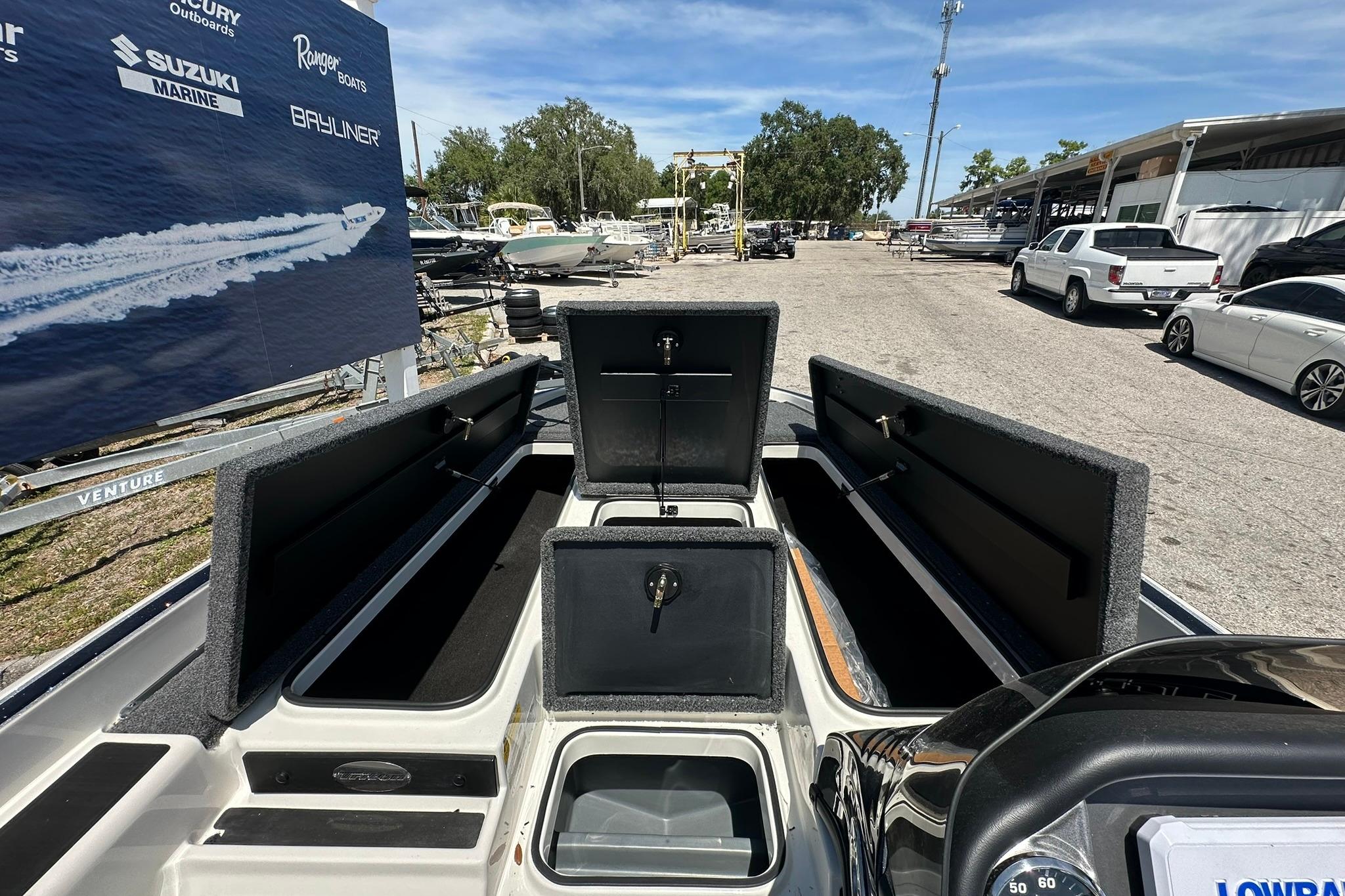 2026 Triton 179 TrX boat with open storage compartments, displayed outdoors on a sunny day.