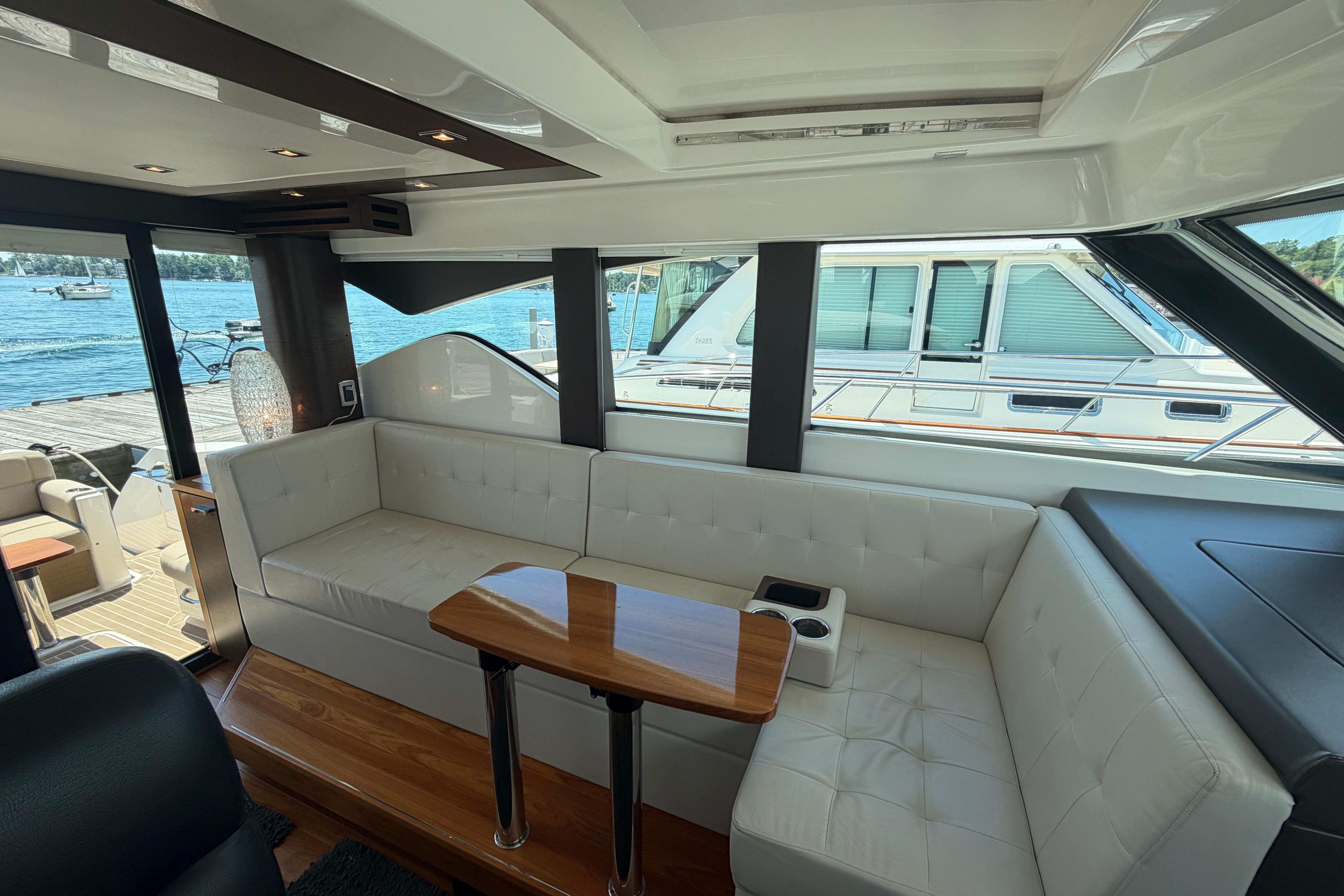 Interior of 2016 Tiara Yachts C39 Coupe with white seating and wooden table.