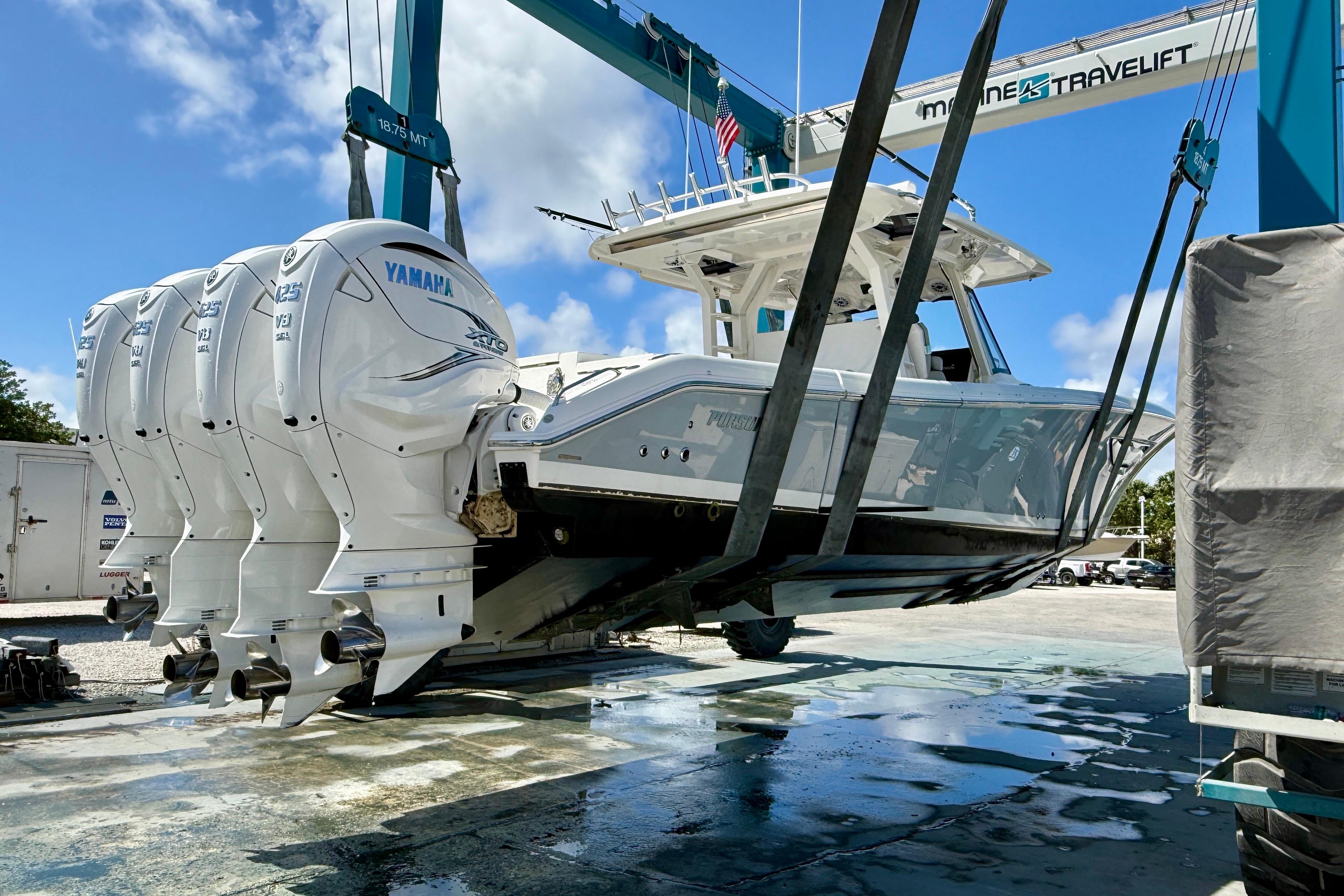2022 Pursuit S 428 Sport boat with Yamaha engines on a lift under blue sky.