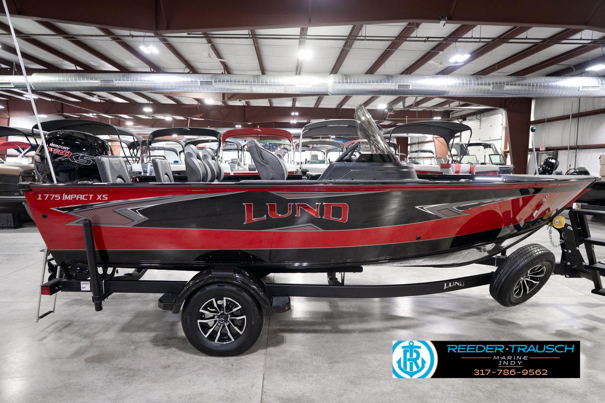 2026 Lund 1775 Impact XS SS boat in showroom, red and black design, on trailer.