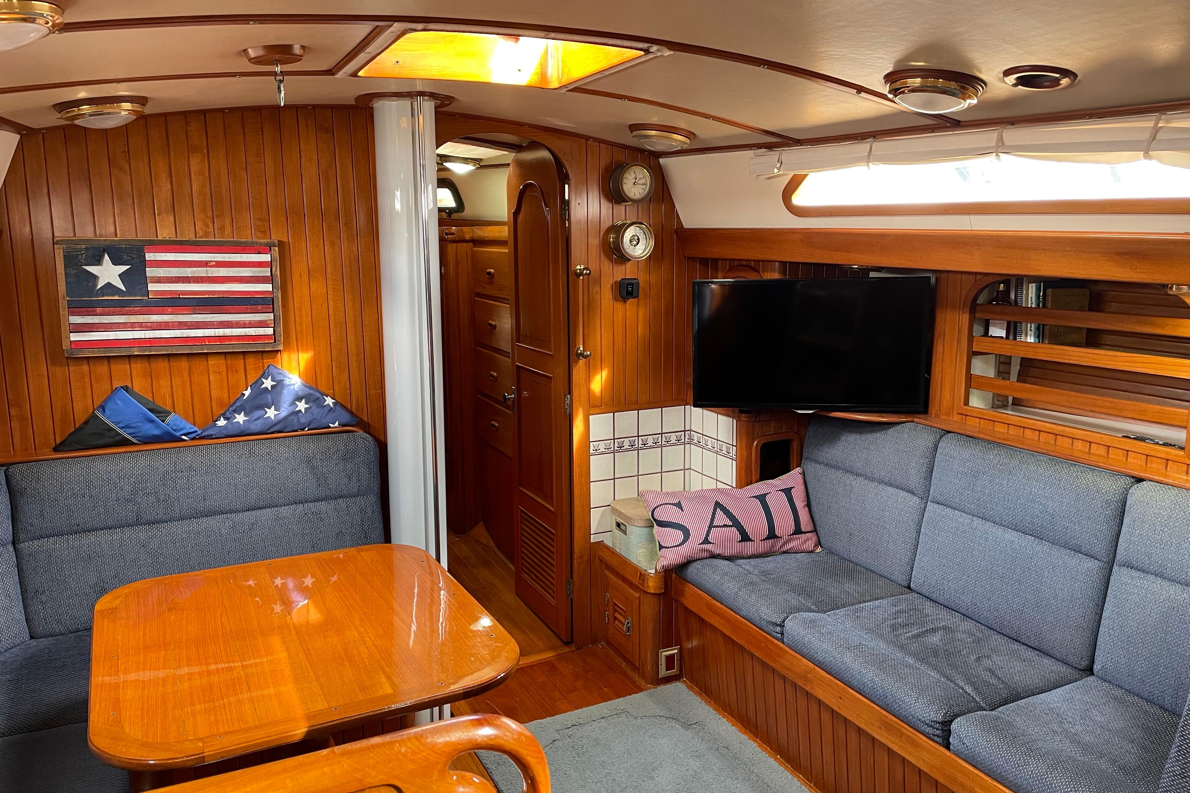 Cozy interior of 1985 Passport 470 Center Cockpit sailboat with wood paneling and nautical decor.