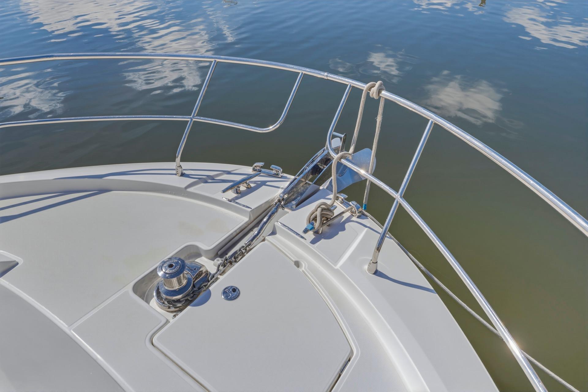 Bow of 2022 Prestige 520 yacht with anchor and railing on calm water.