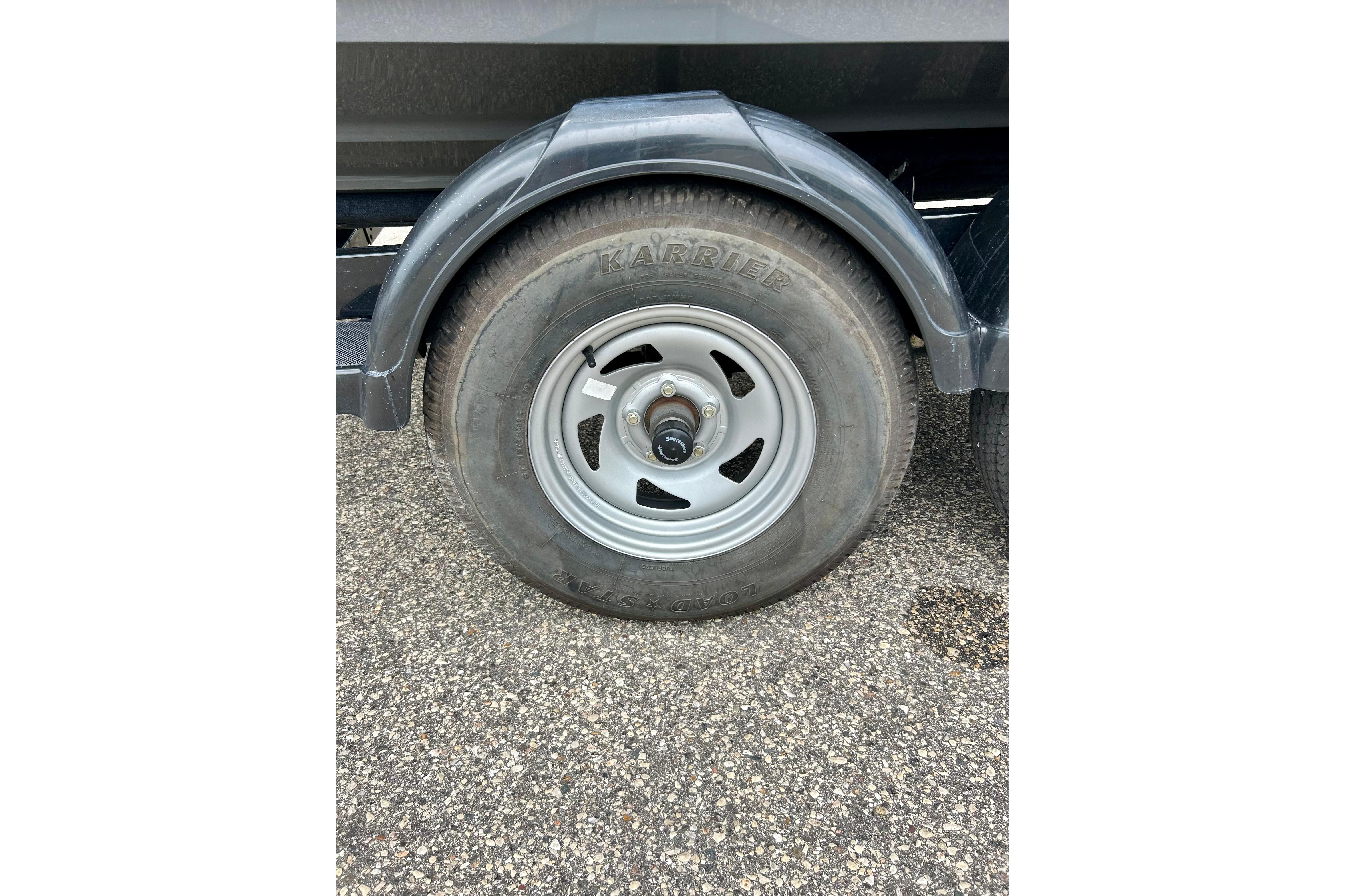 Trailer wheel of a 2015 Yamaha Boats AR210 on asphalt surface.