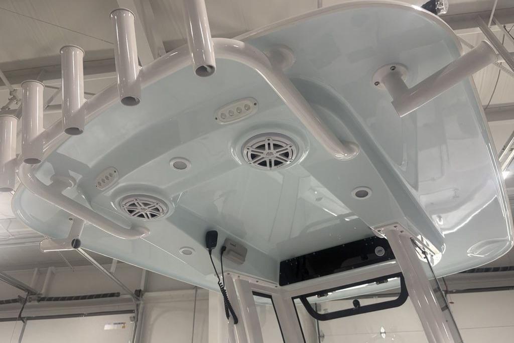2026 Sportsman Masters 227 boat T-top with rod holders and speakers in a showroom.