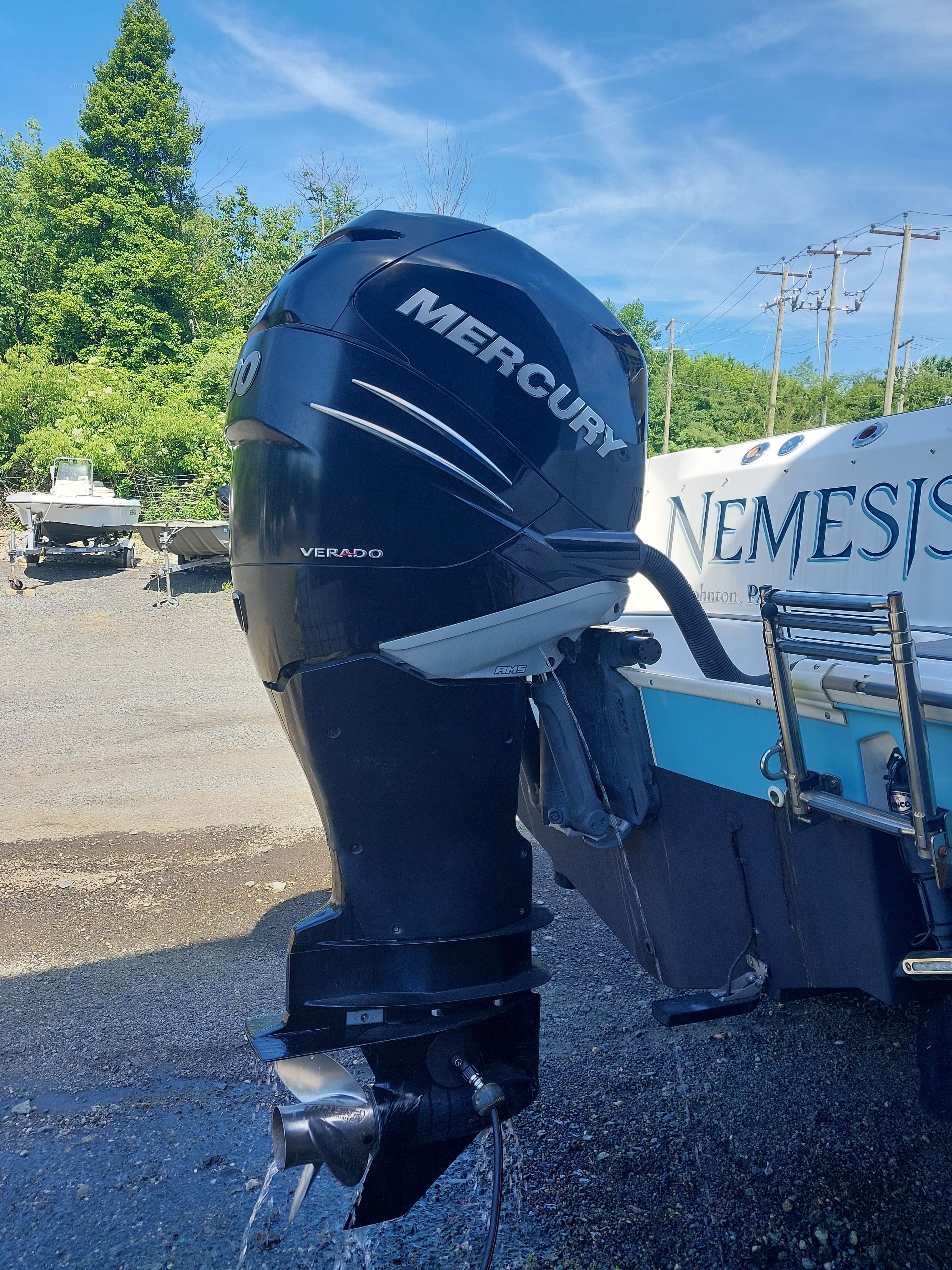 A Mercury outboard motor is attached to a Boston Whaler 240 Outrage boat, which is on land.