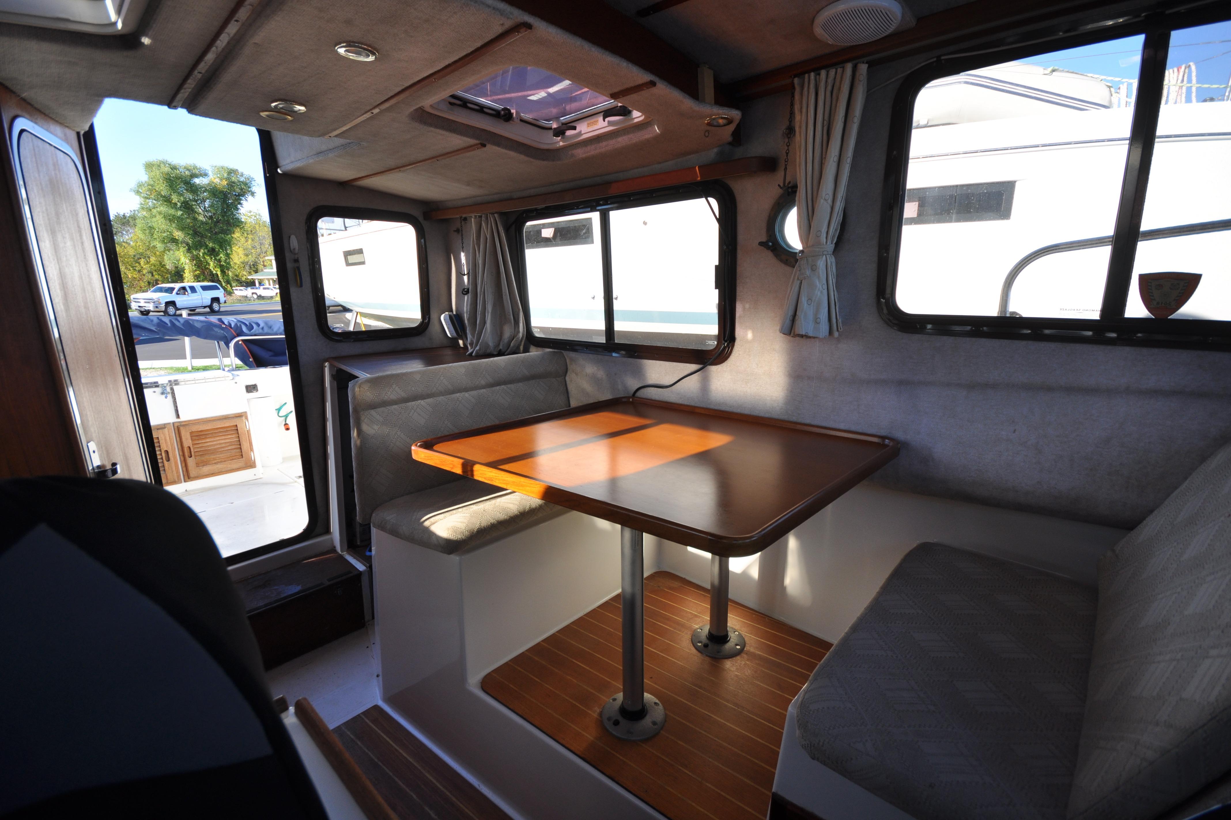 Interior of 2007 Ranger Tug R-25, featuring a cozy dining area with wooden table.