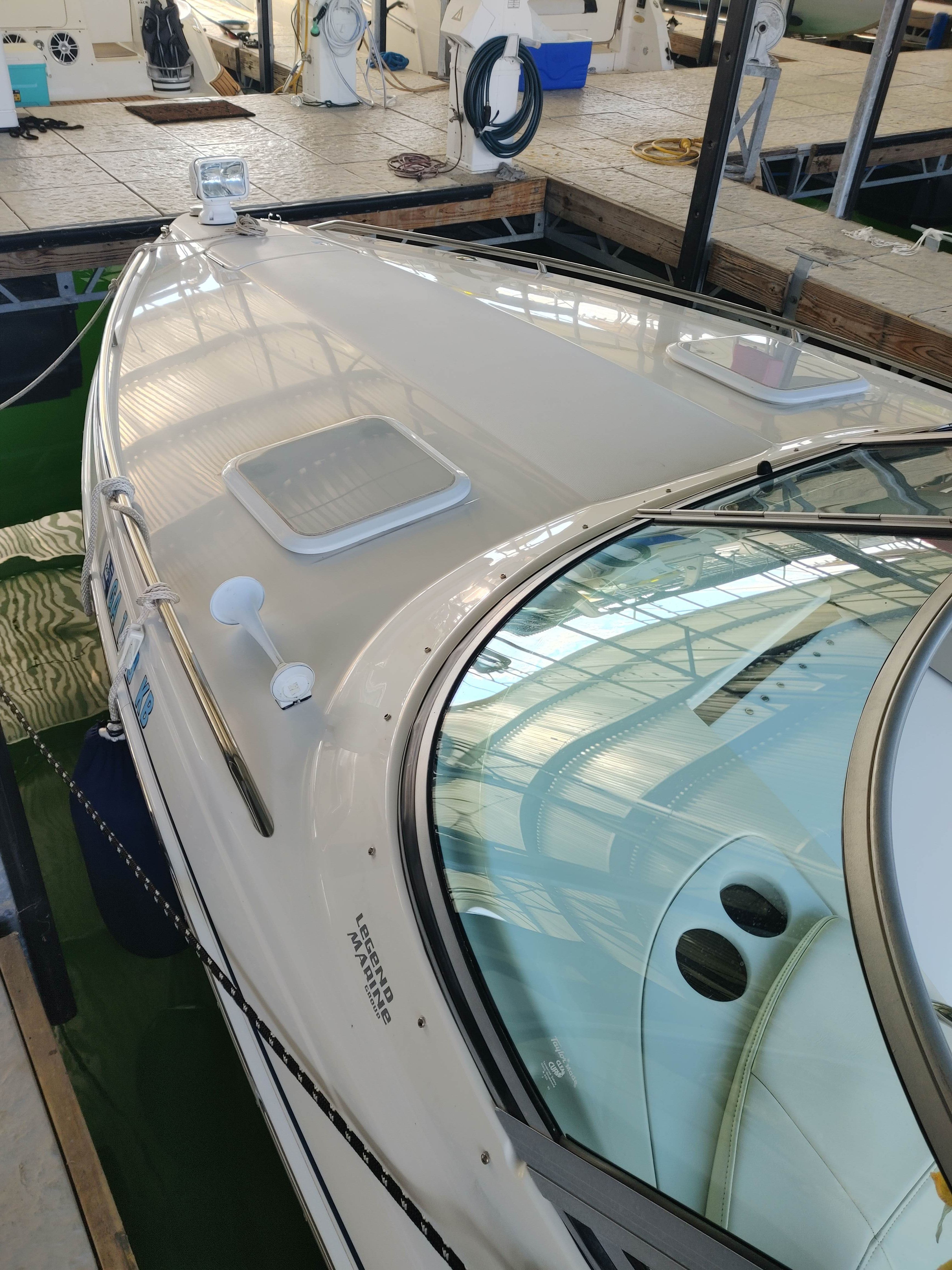 A white boat docked in a marina, featuring a sleek deck and a porthole.