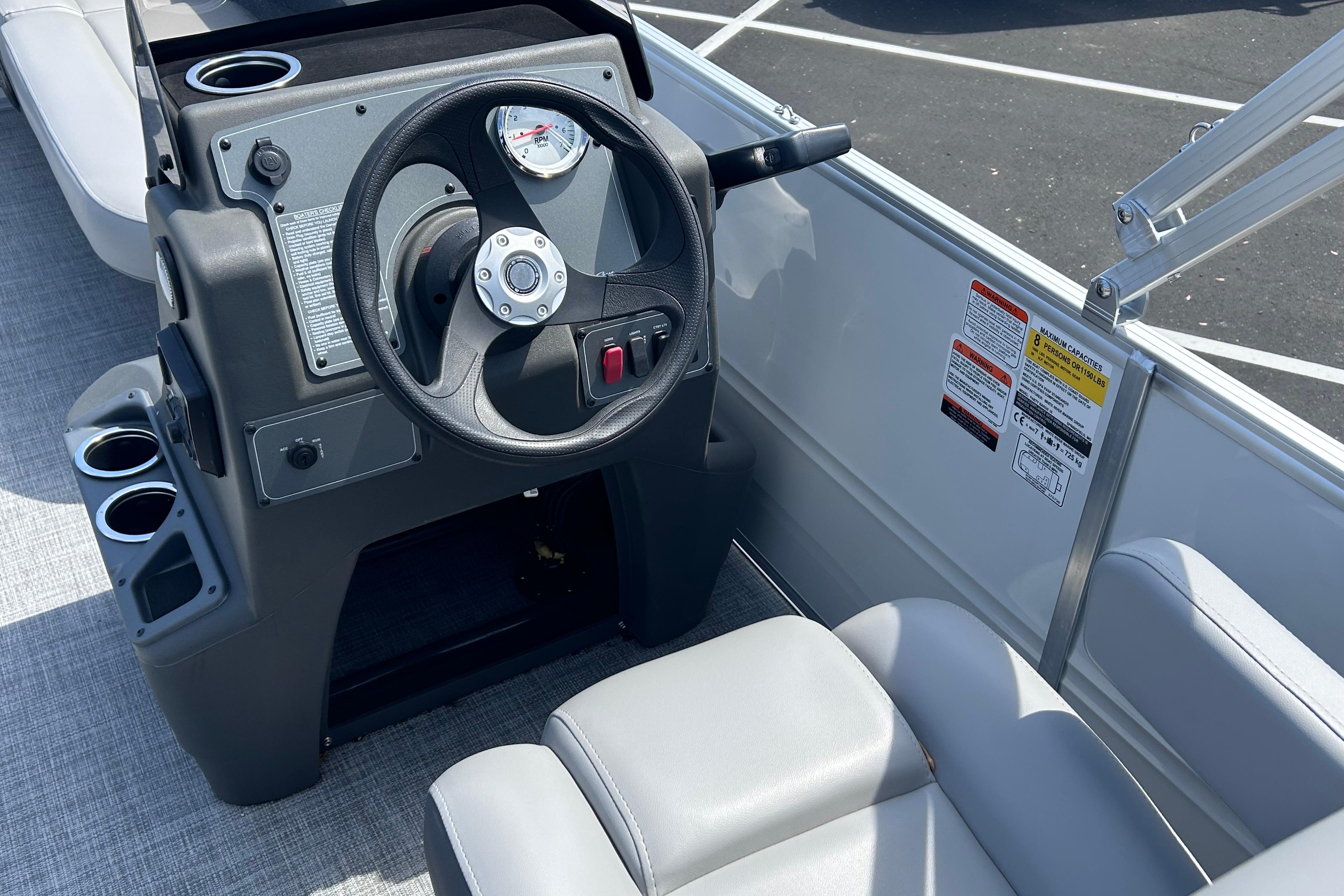 2026 Sun Tracker Party Barge 16 DLX steering console with cup holders and seating.