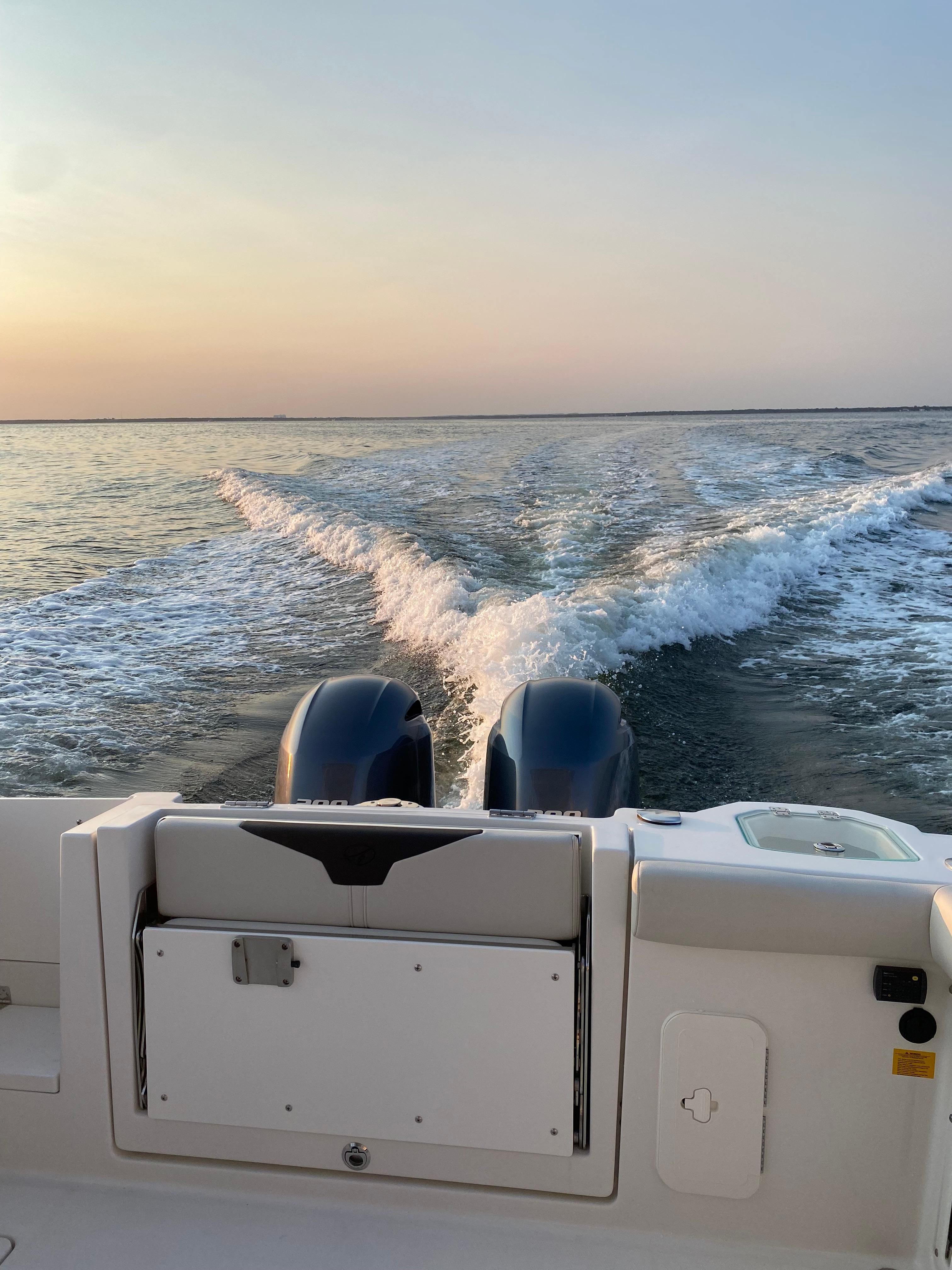 Sailfish 276 DC 2022 boat cruising on calm sea at sunset.