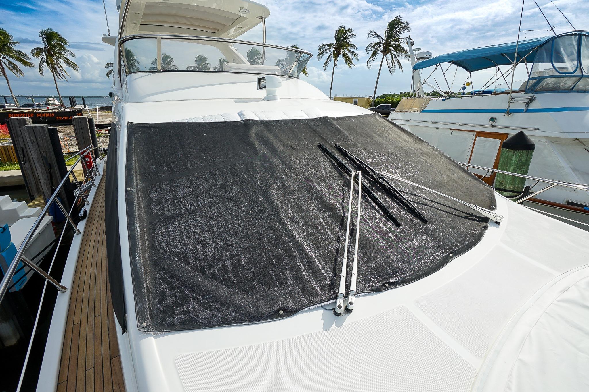 2014 Azimut 54 Flybridge yacht with covered windshield, docked near palm trees.