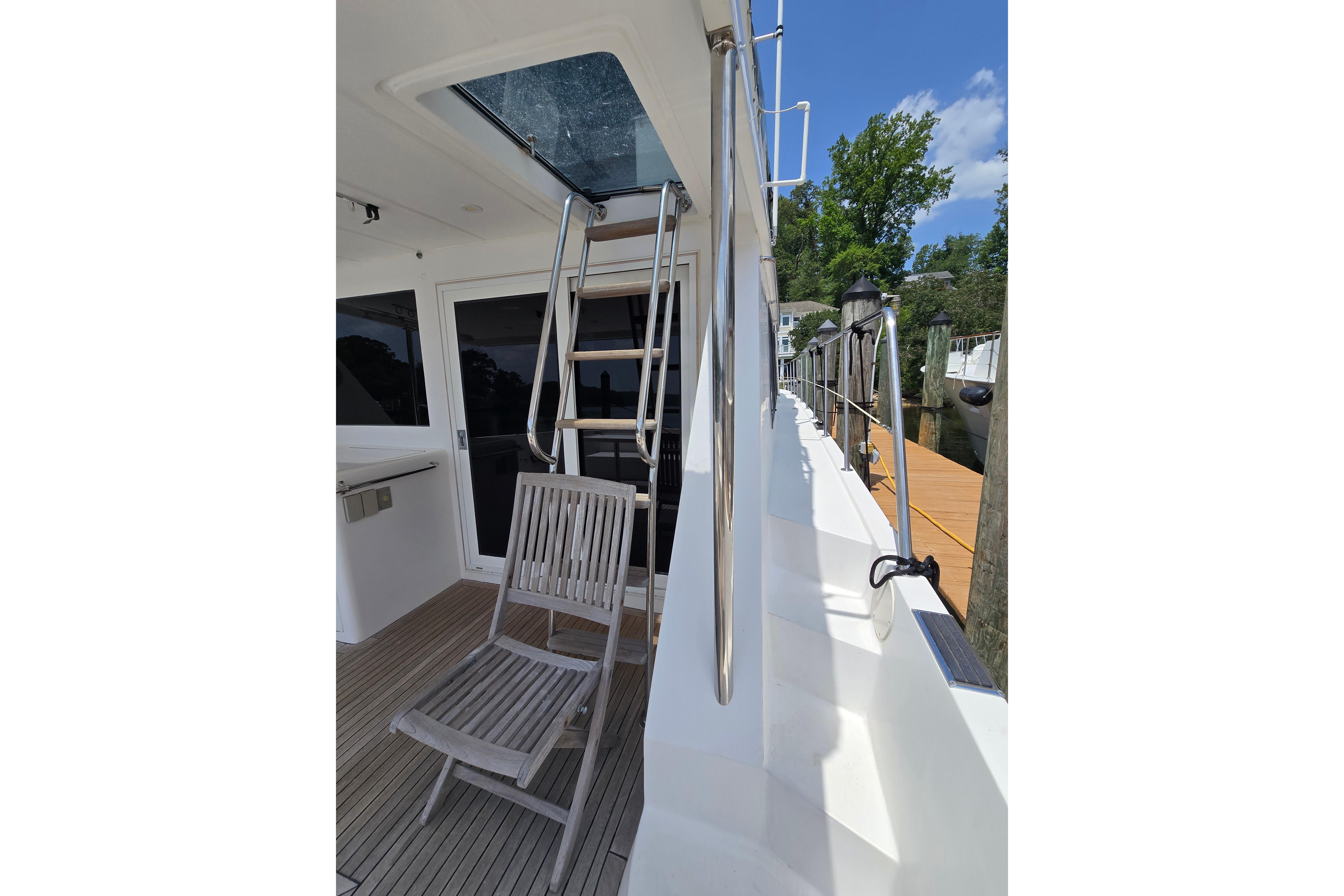Side deck of 2004 Grand Harbour 58 yacht with ladder and wooden chair.