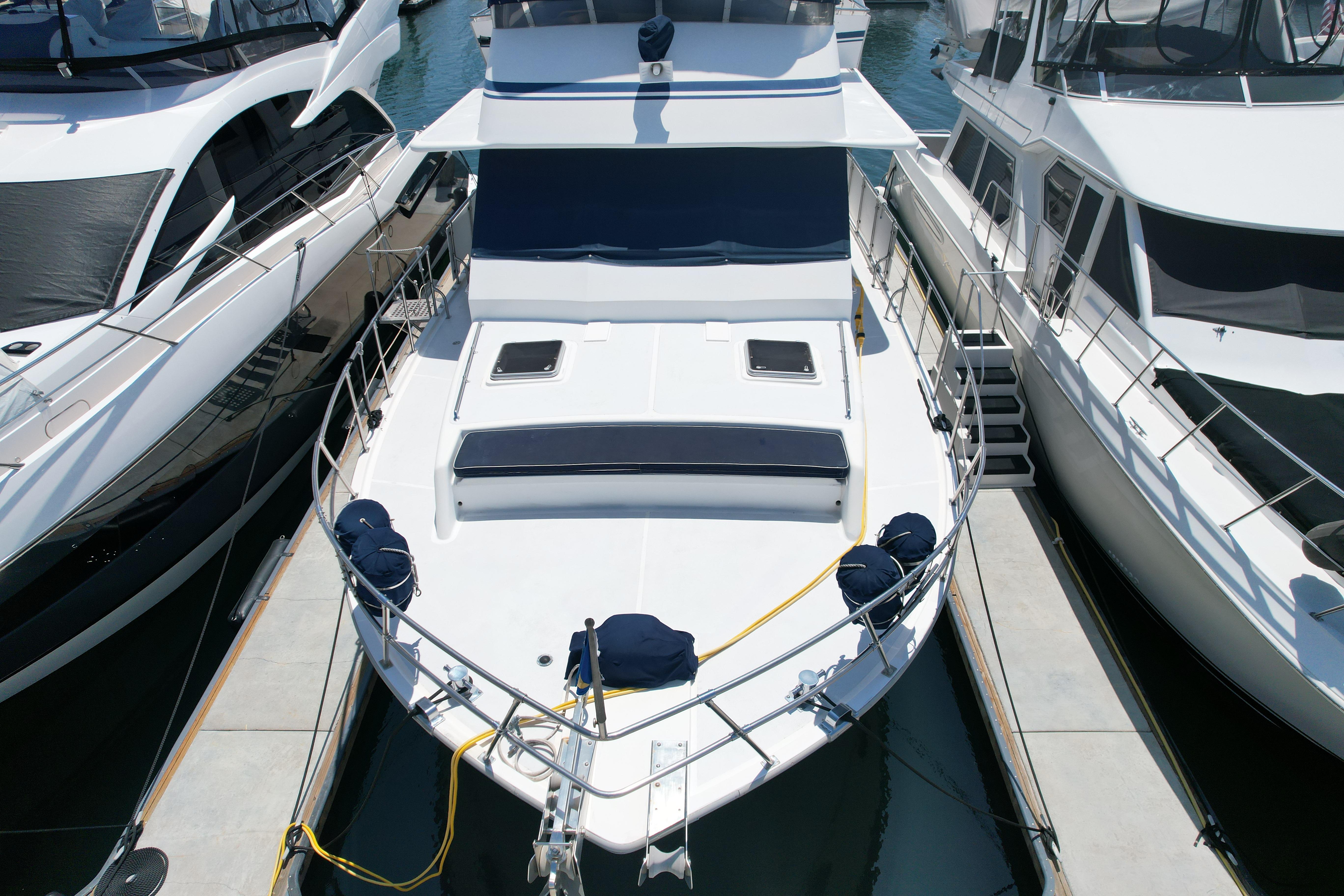 1988 Sea Ranger 51 Motor Yacht docked between two boats at a marina.
