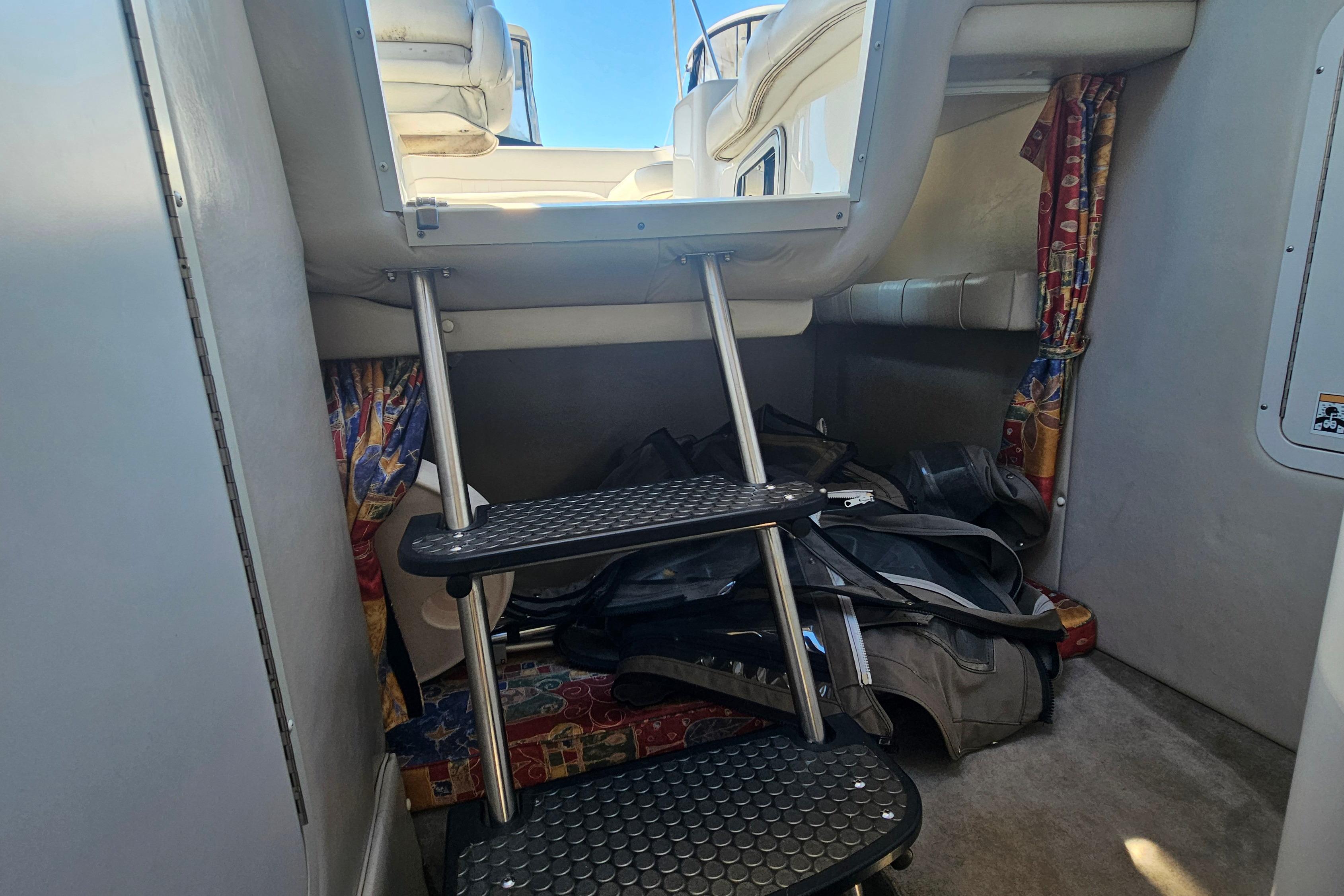 Interior cabin of 2000 Crownline 242 CR boat with steps and colorful curtains.