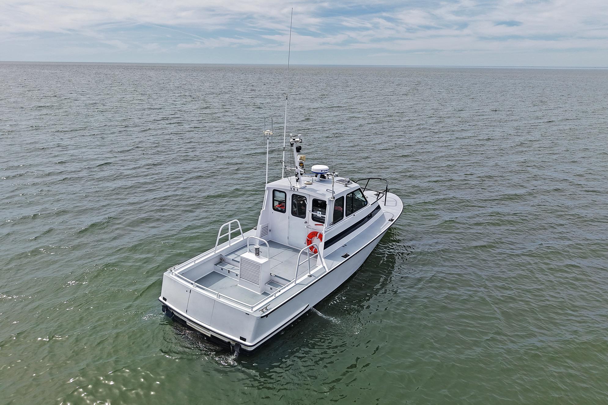 1990 Boston Whaler 36 Defiance boat cruising on open water under a cloudy sky.