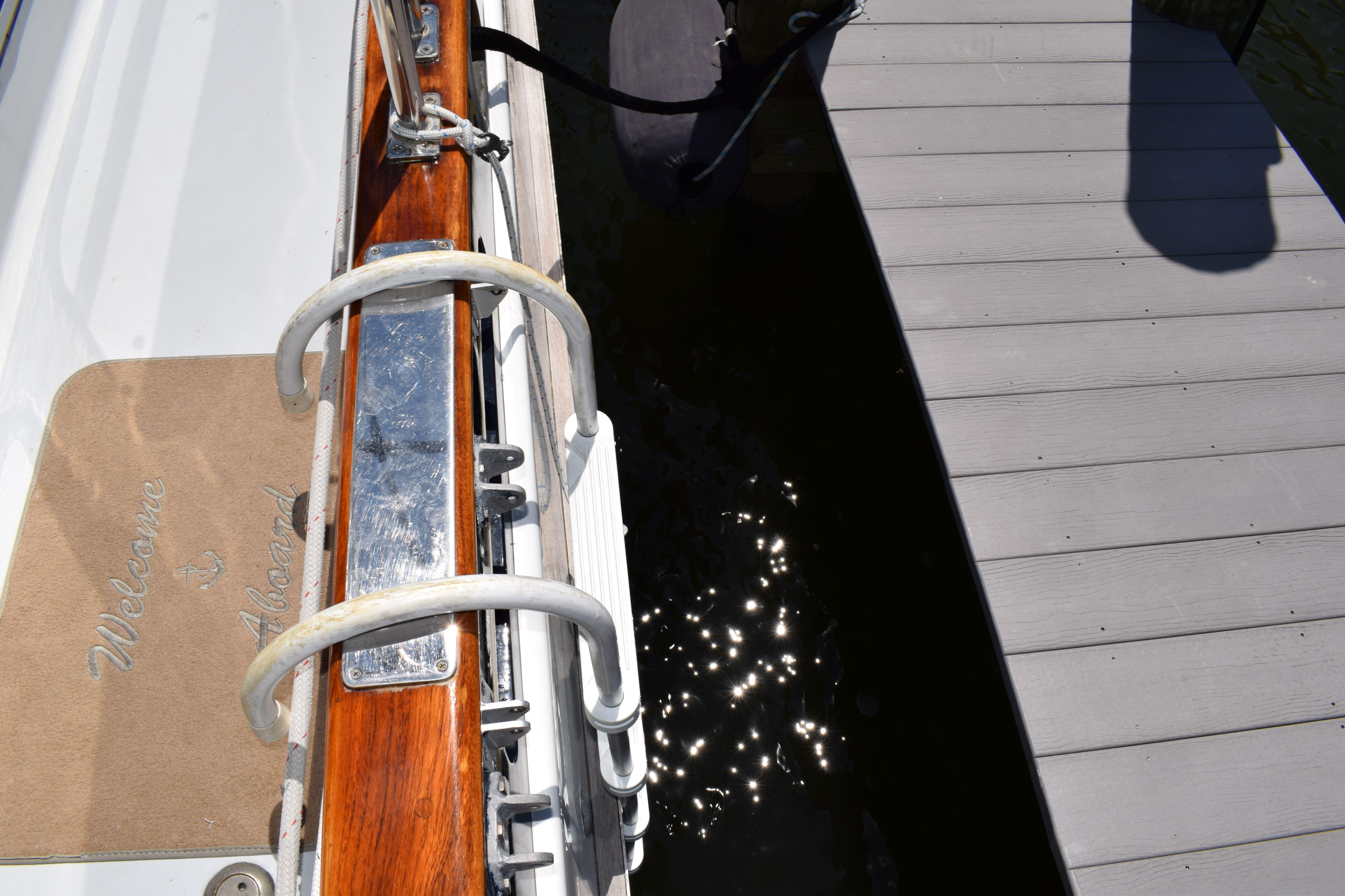 1980 Cheoy Lee 52 Motorsailer docked, featuring a "Welcome Aboard" mat and polished wood railing.
