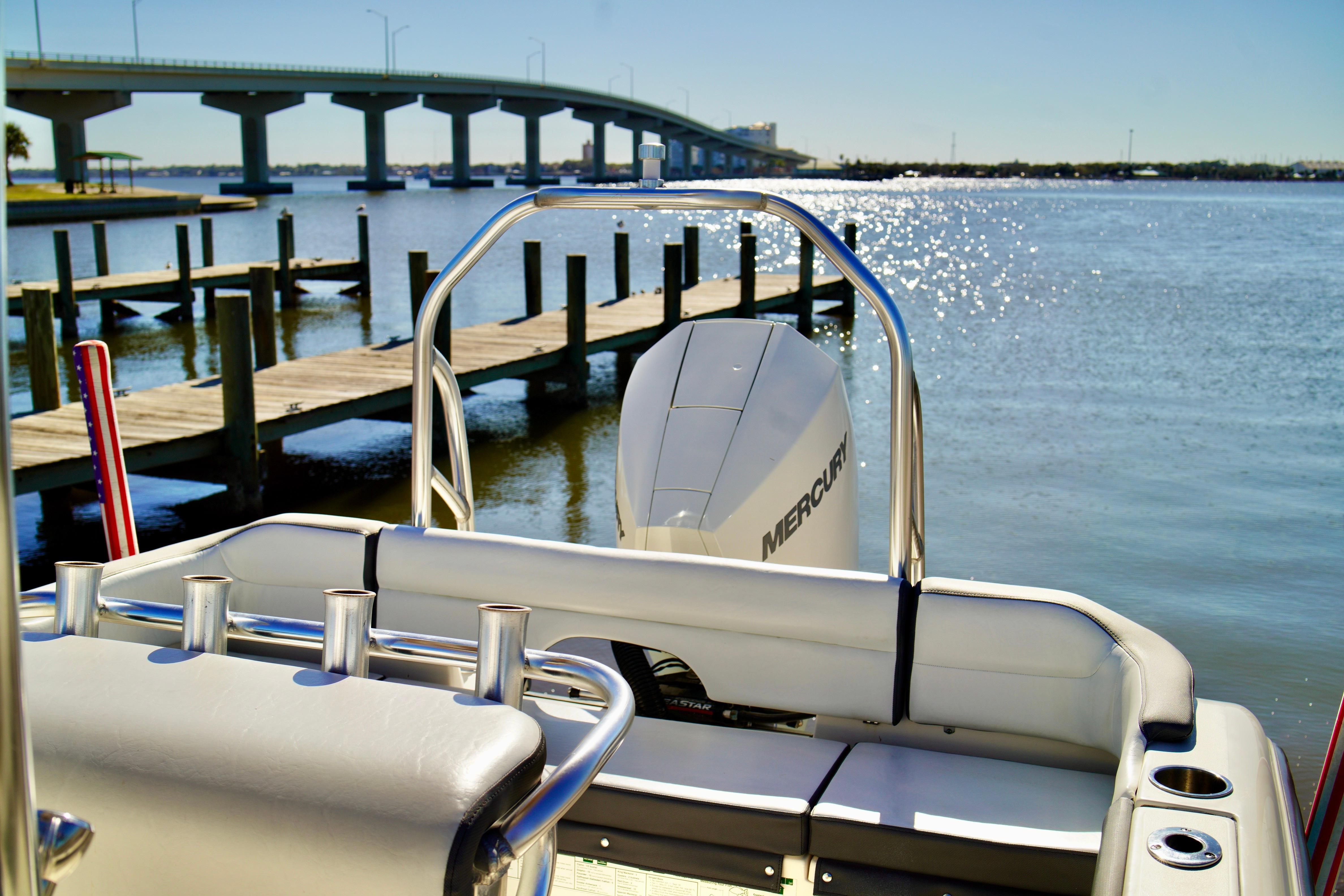 2020 Key West 203 FS boat with Mercury engine docked near a bridge on a sunny day.