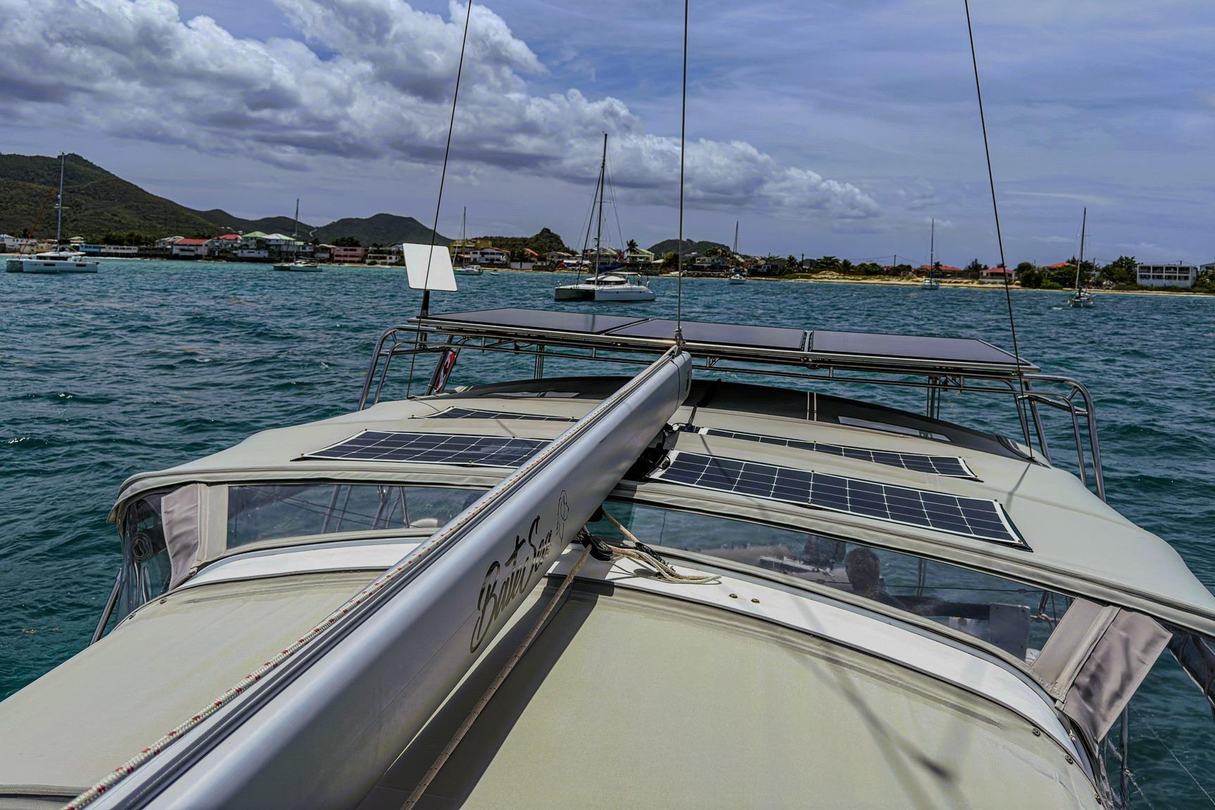 2020 Beneteau Oceanis 46.1 sailboat with solar panels on deck, anchored in scenic bay.