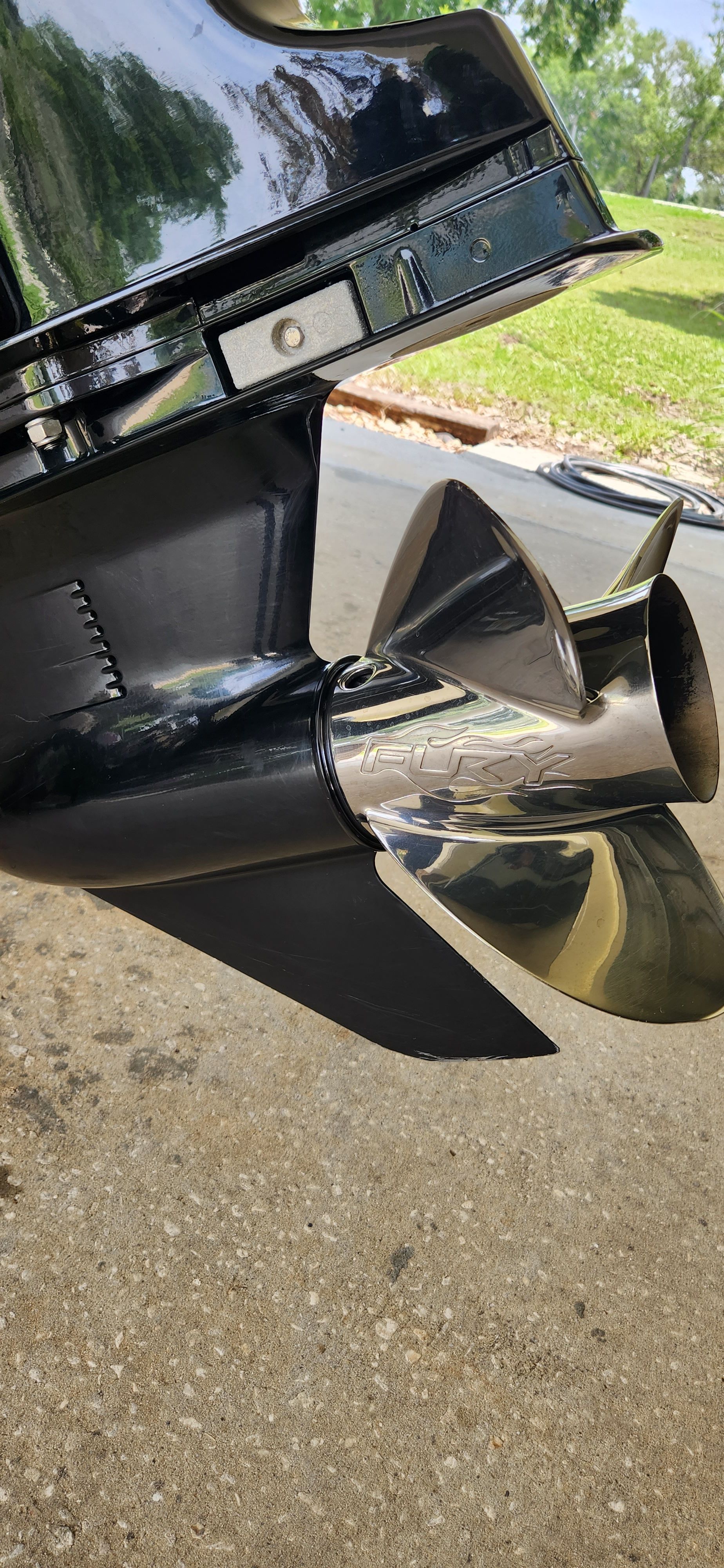 Close-up of a shiny propeller on a boat, resting on a concrete floor.