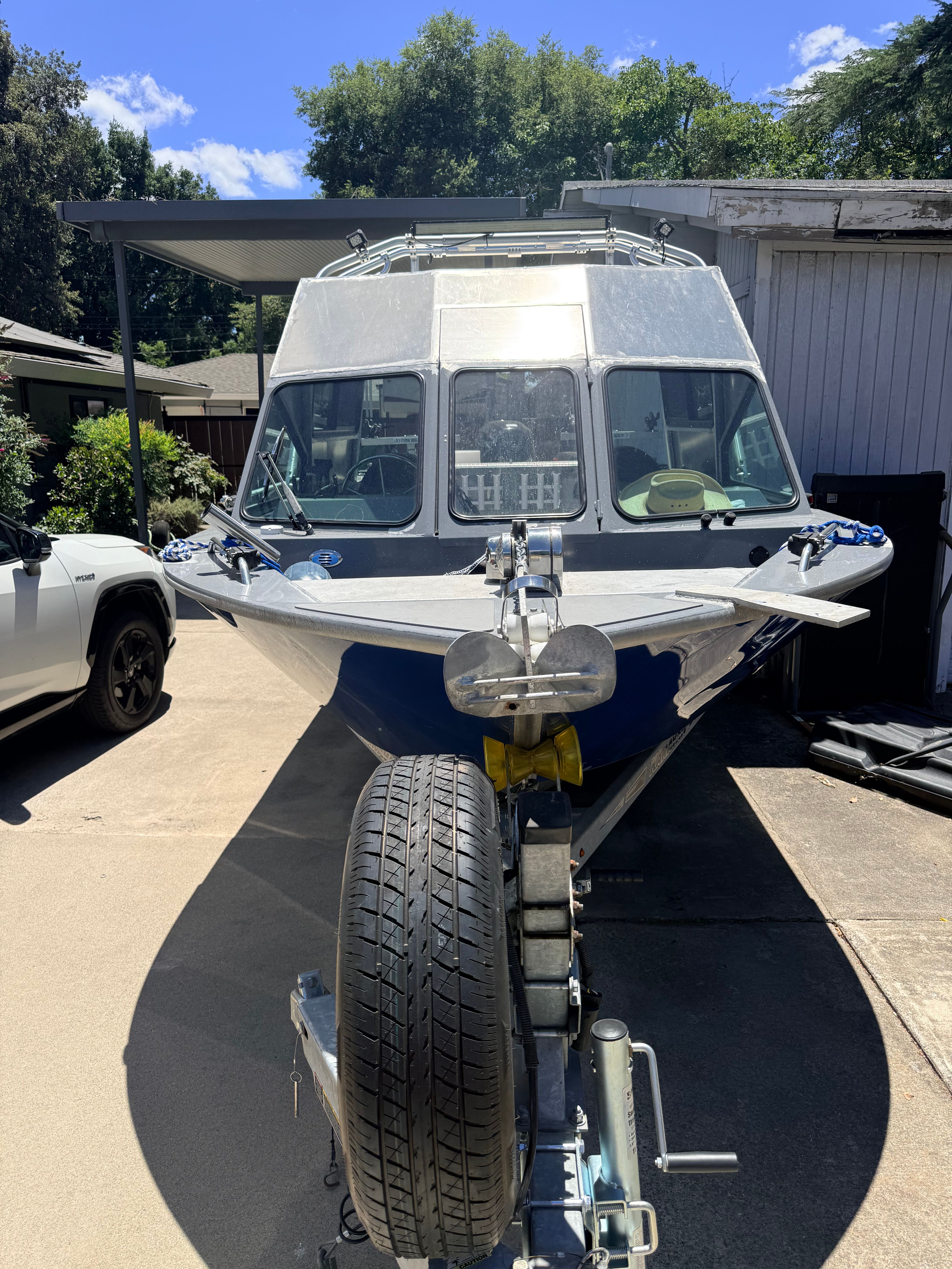 A 2017 River Hawk Coastal Series 20’ boat on a trailer in a driveway.