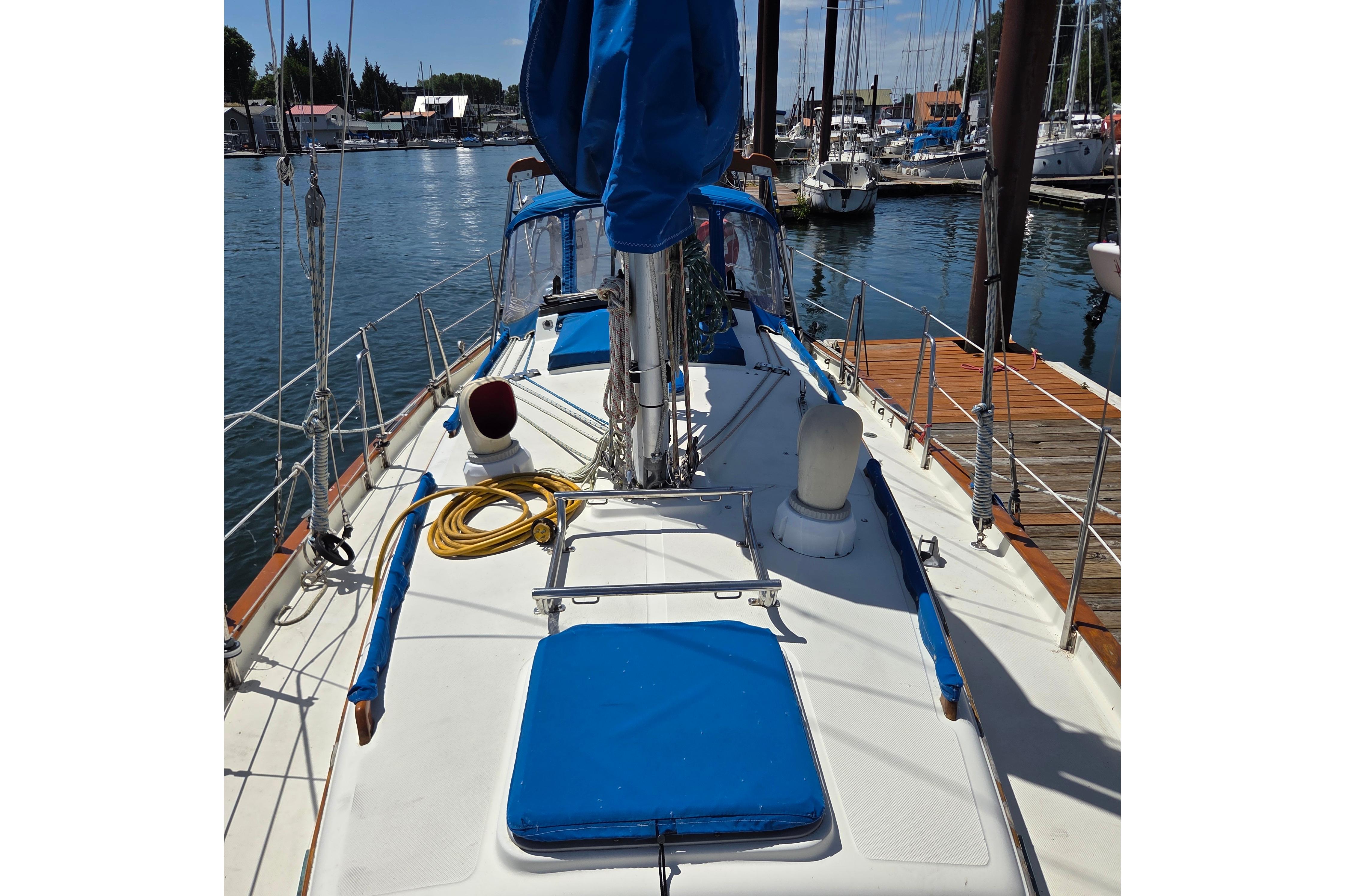 1983 Pacific Seacraft 34 sailboat docked at marina, featuring blue accents and nautical equipment.