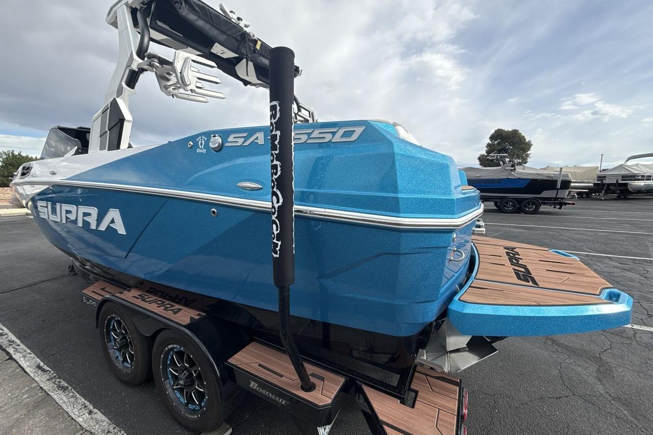 2024 Supra SA 550 boat in vibrant blue, parked on a trailer.