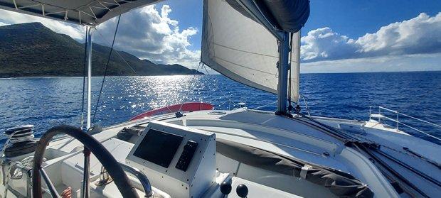 Lagoon 440 catamaran sailing on open sea, sunny day, scenic coastal view, 2010 model.