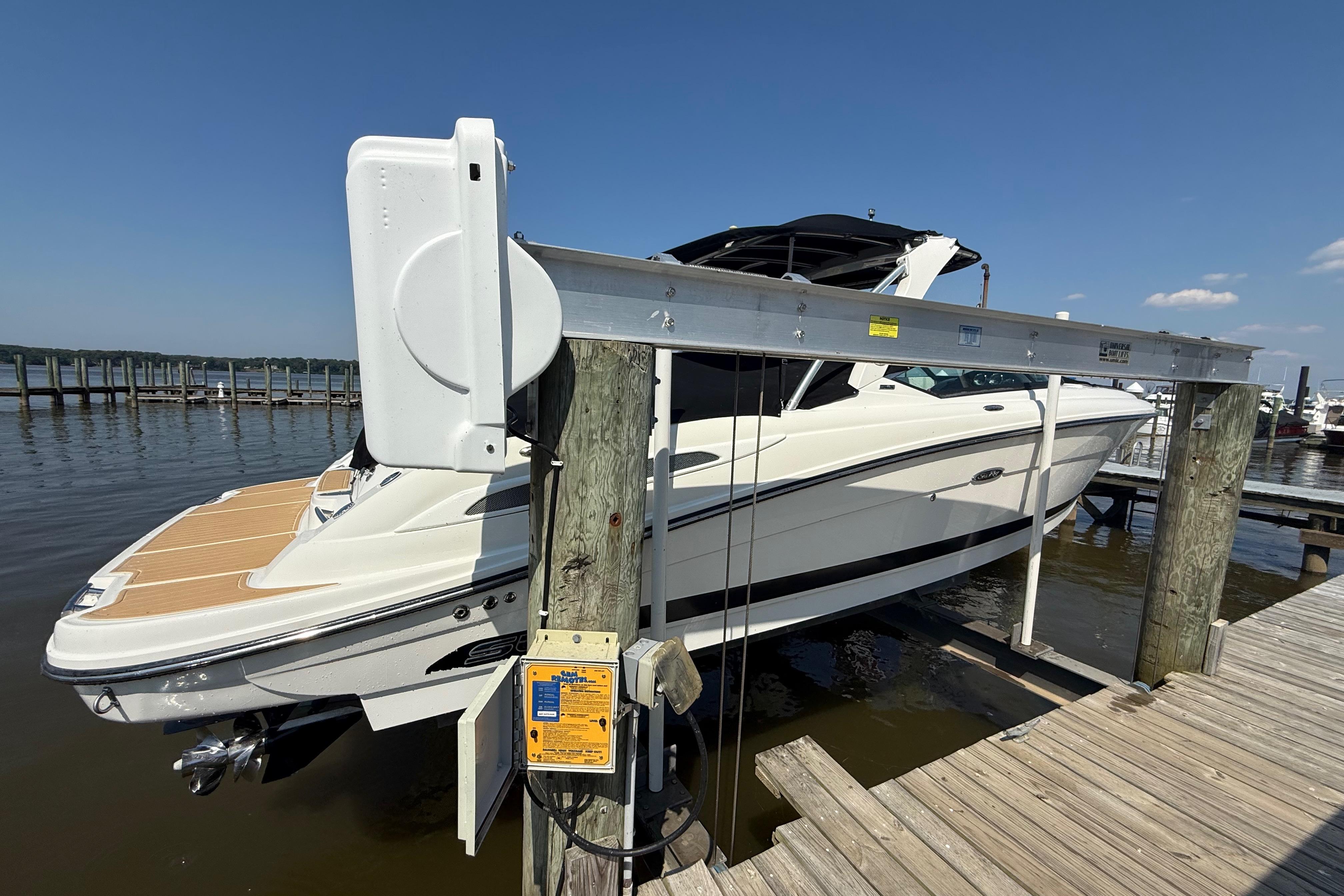 2011 Sea Ray 270 SLX boat on lift at marina dock under clear sky.