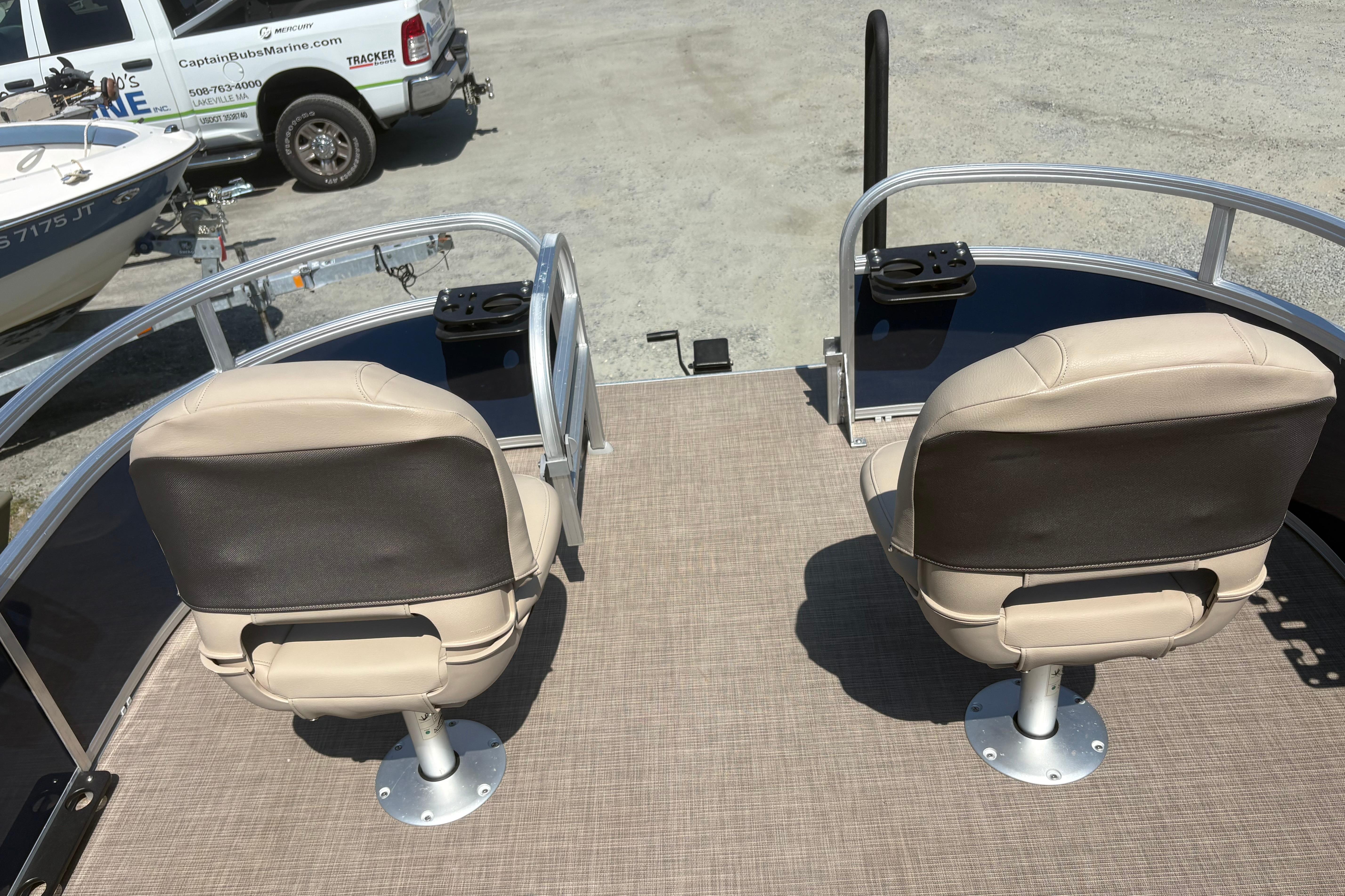 2024 Sun Tracker Bass Buggy 16 DLX pontoon boat with beige seating and fishing rod holders.