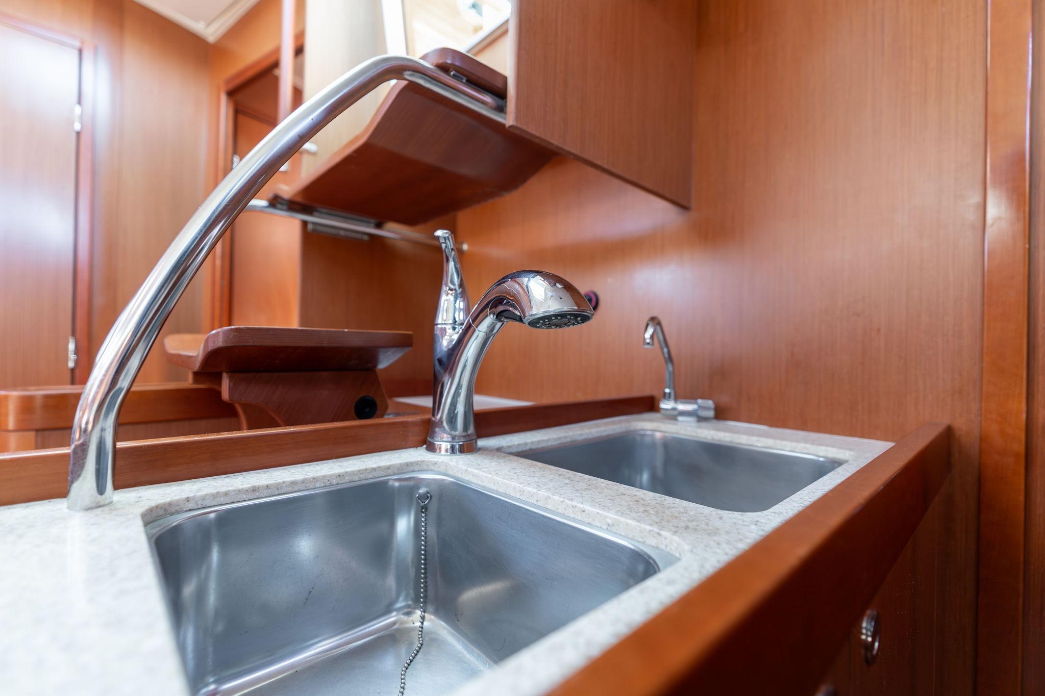 Galley sink in 2013 Beneteau Oceanis 50 yacht with wooden cabinetry.