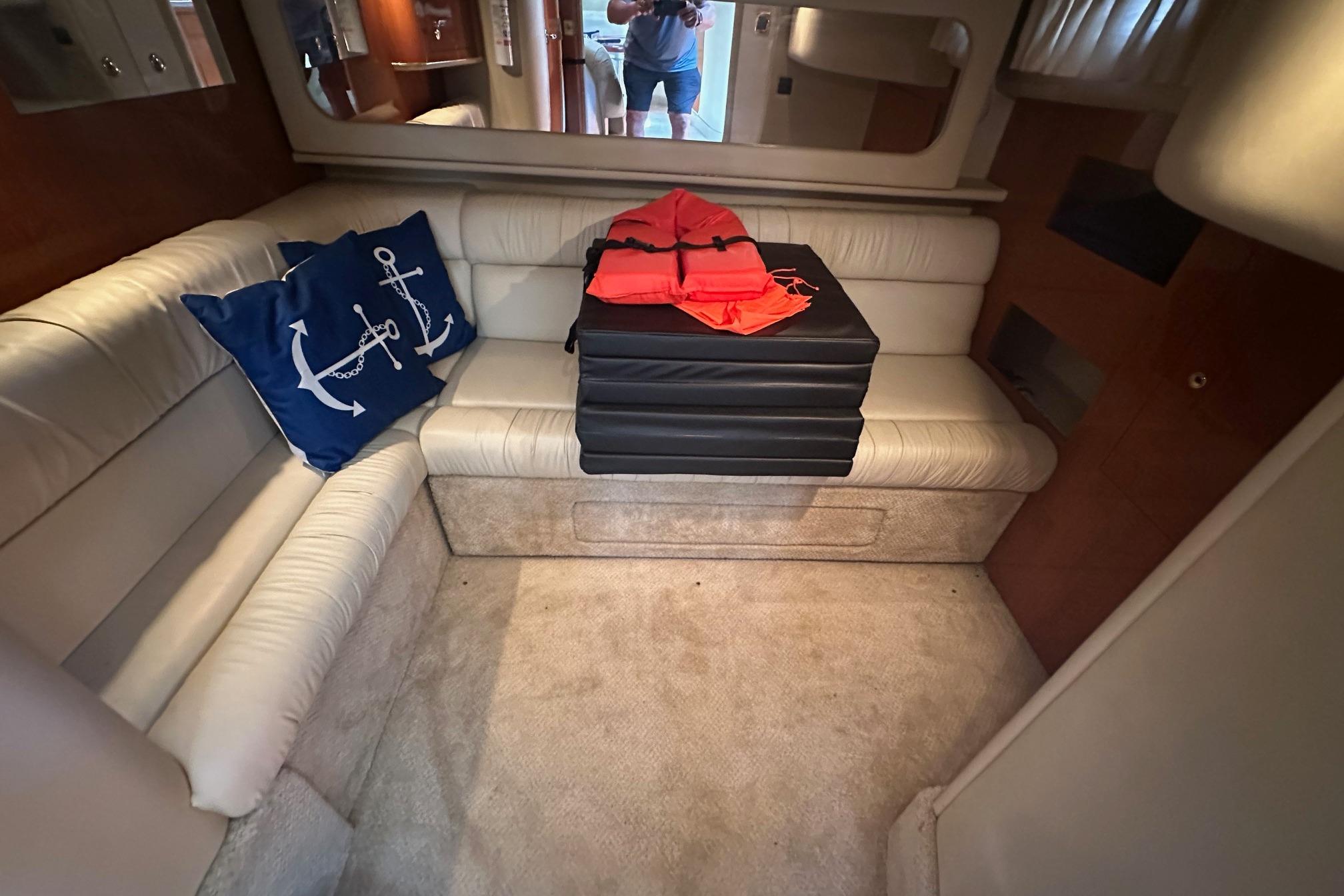 Interior of 2001 Sea Ray 410 Sundancer with white seating and nautical-themed decor.