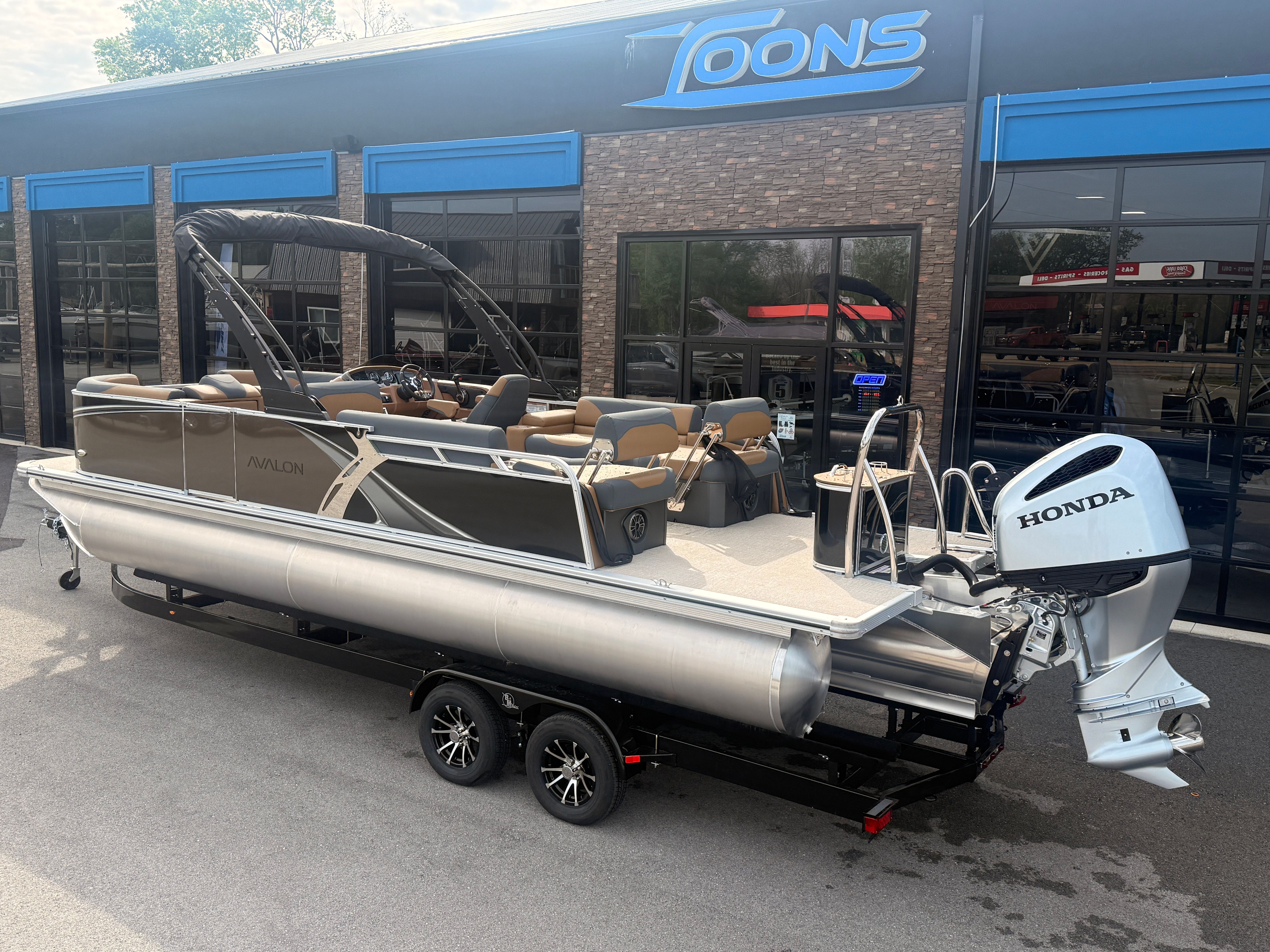 2026 Avalon 2385 LSZ pontoon boat with Honda engine outside a store.