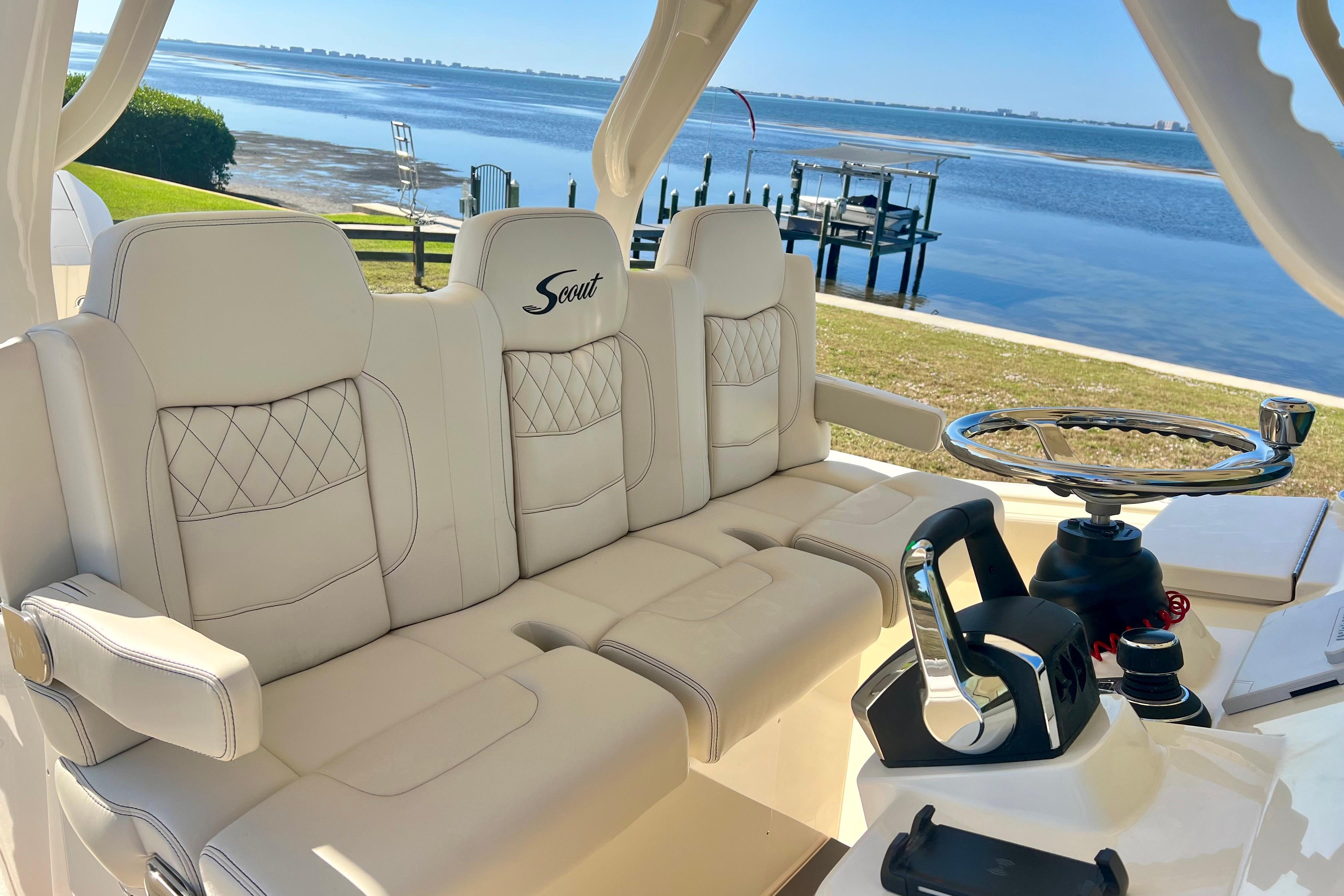 Luxurious interior of 2026 Scout 357 LXF boat with plush seating and scenic waterfront view.