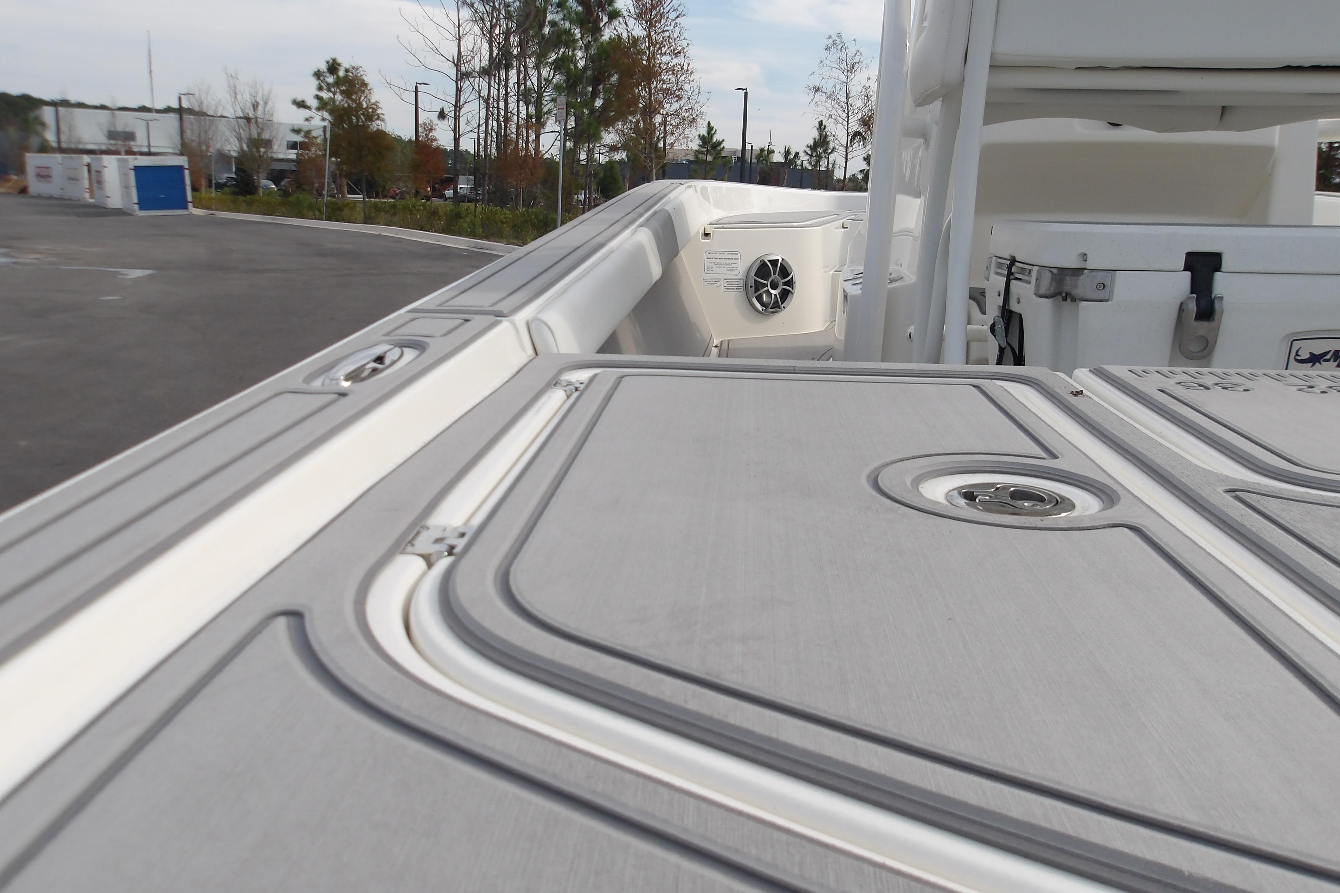 2026 Mako 24 APEX boat deck with storage compartments and speaker, parked outdoors.