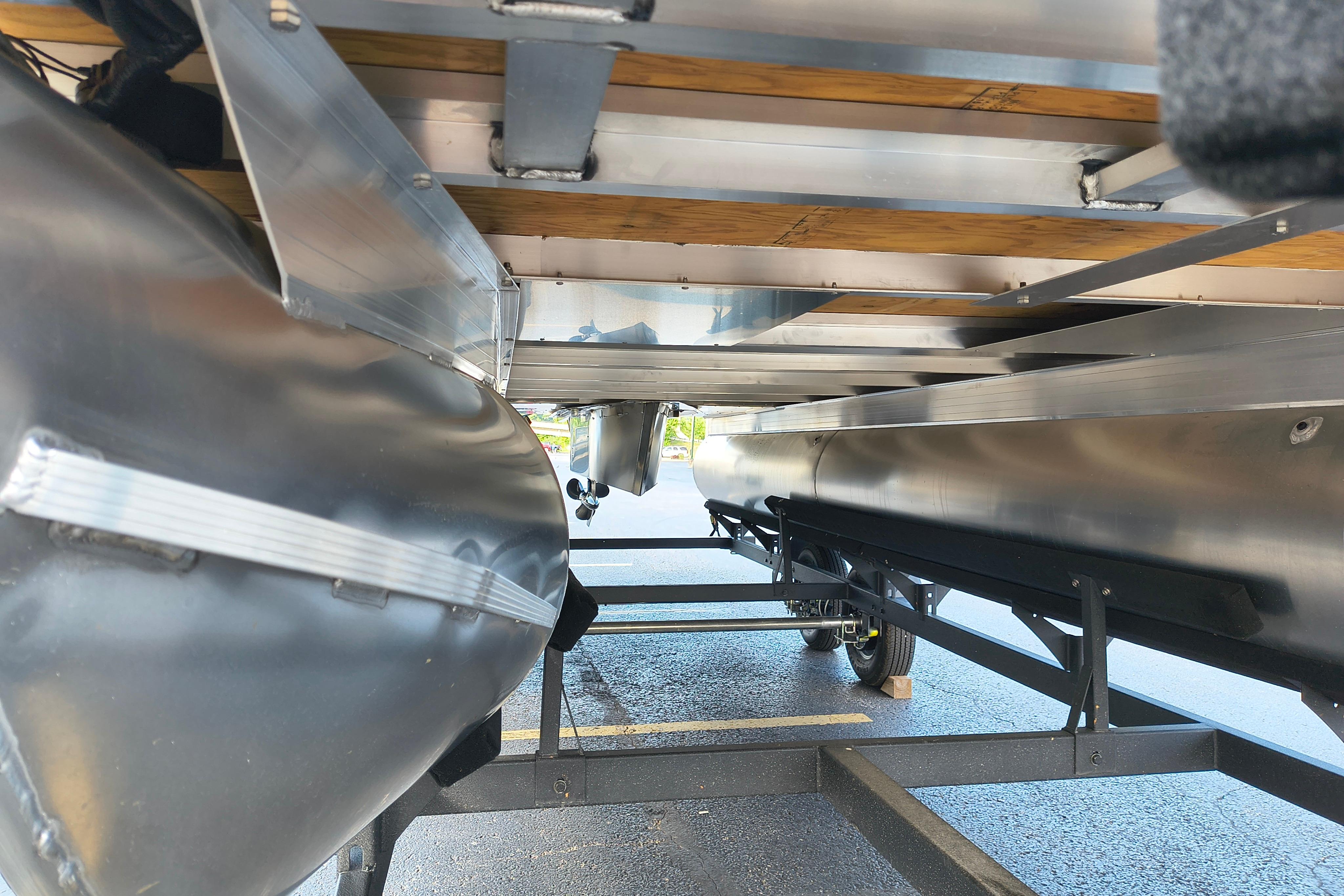 Underneath view of 2026 Sun Tracker Fishin' Barge 22 DLX pontoon boat on trailer.